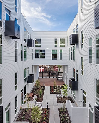 Contemporary apartment complex showcasing a spacious courtyard with landscaped gardens and sleek, modern architecture.