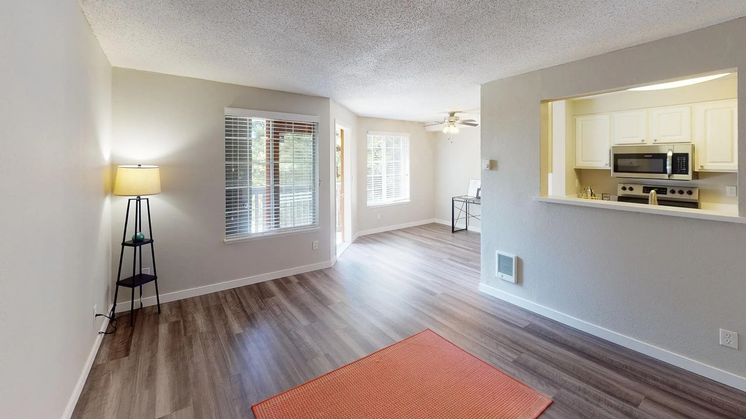 Modern apartment showcasing open-plan layout with sleek hardwood floors, bright natural lighting, and a stylish kitchen view.