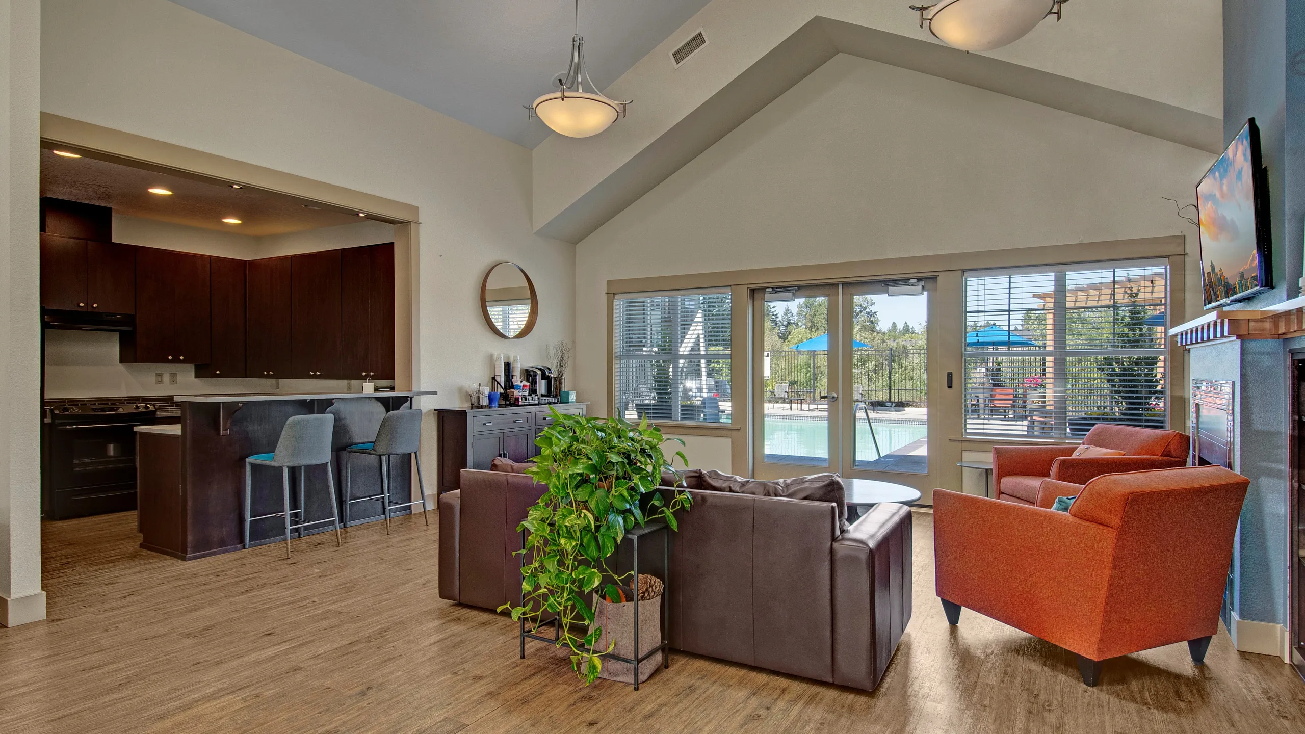 Inviting living room with vaulted ceilings, stylish furnishings, and expansive windows offering a view of the poolside oasis.