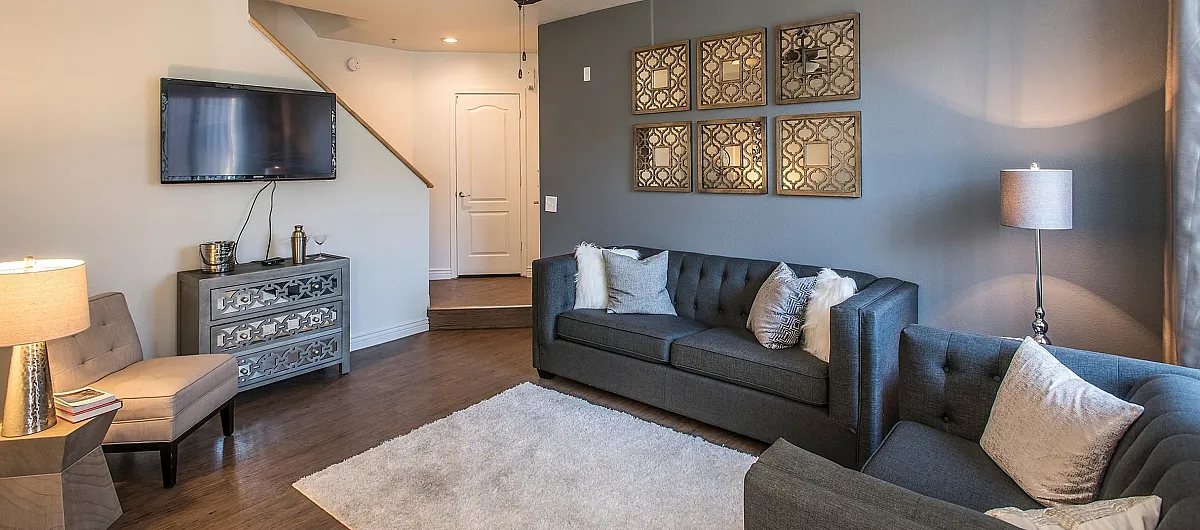 Inviting living room with chic decor, featuring elegant grey sofas, stylish wall art, and natural light highlighting the cozy ambiance.