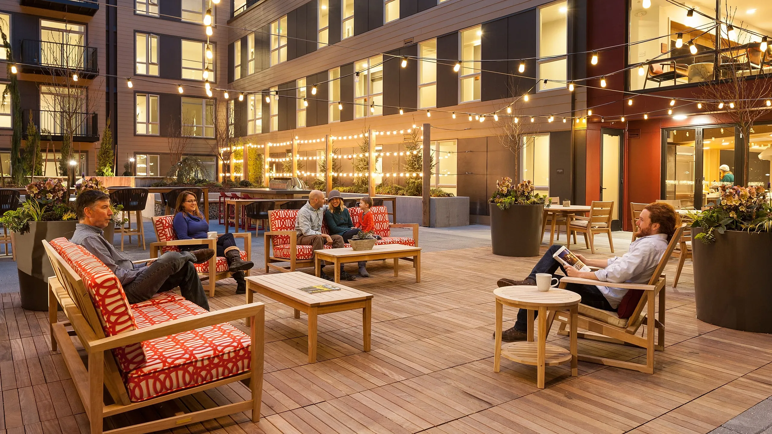 Inviting apartment complex courtyard with warm string lights, stylish outdoor seating, and relaxed atmosphere.