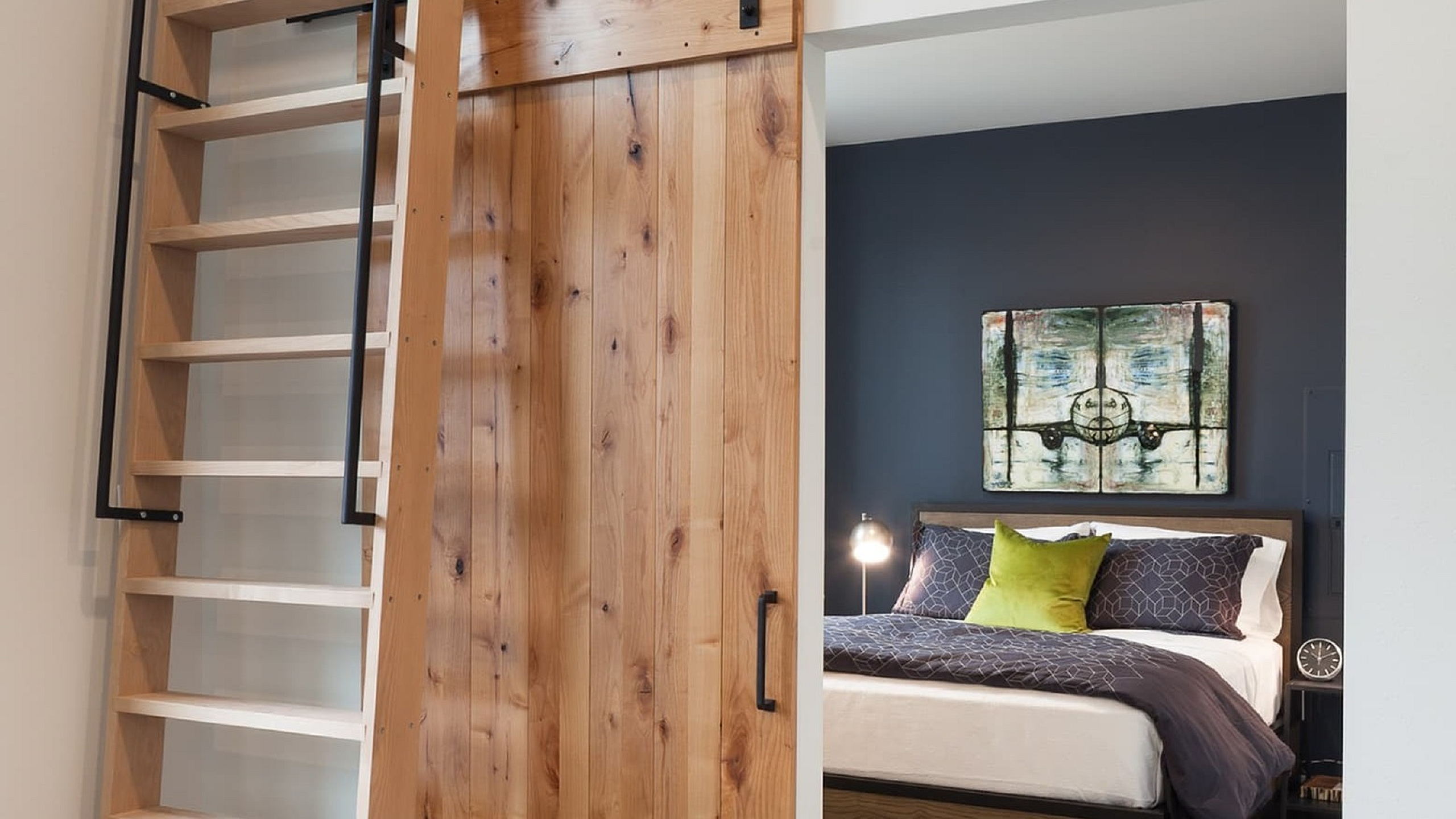 Chic apartment showcasing a loft ladder, rustic sliding barn door, and cozy bedroom with stylish d&eacute;cor.