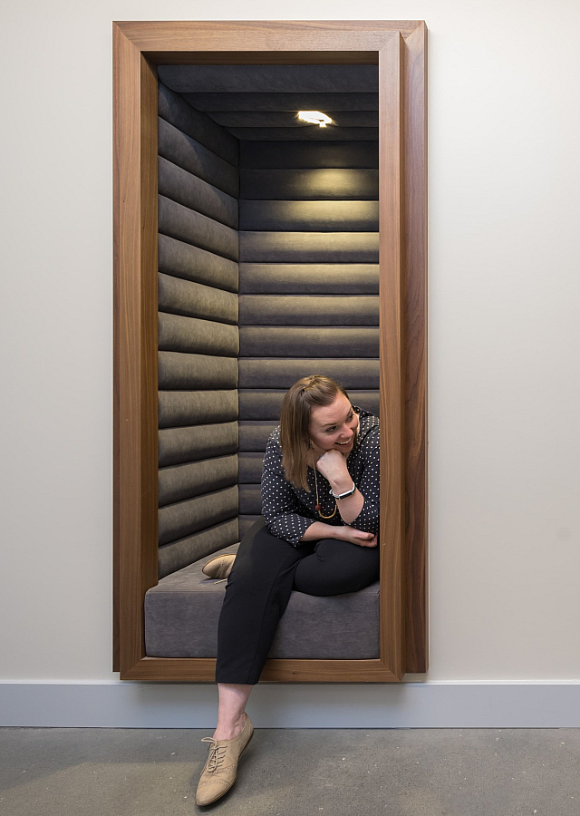 Modern and cozy seating pods with wood trim, featuring two women enjoying a lively conversation in a stylish interior setting.