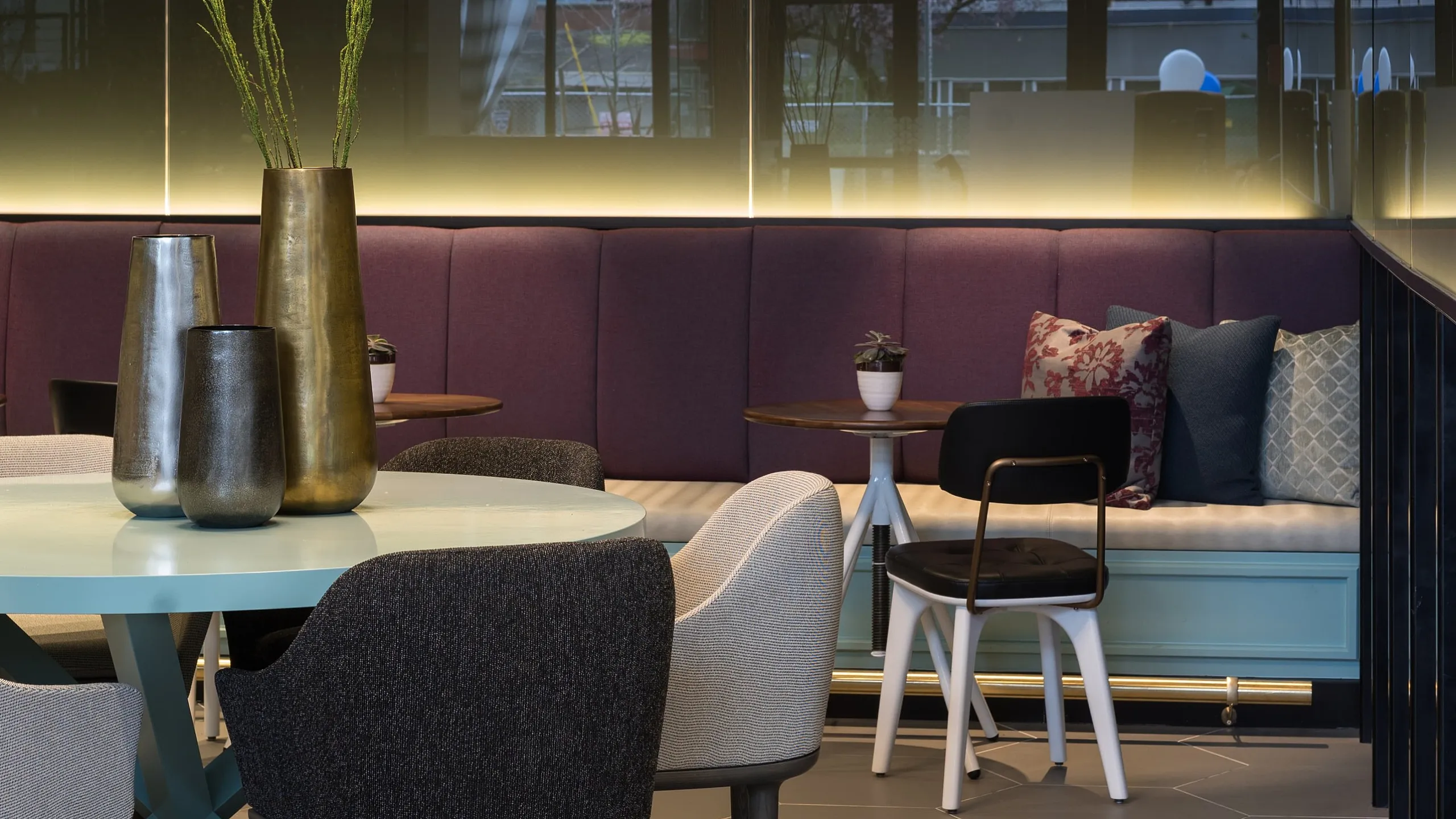 Chic dining area featuring modern chairs around a sleek round table, enhanced by striking pendant lighting and a plush purple bench seating.