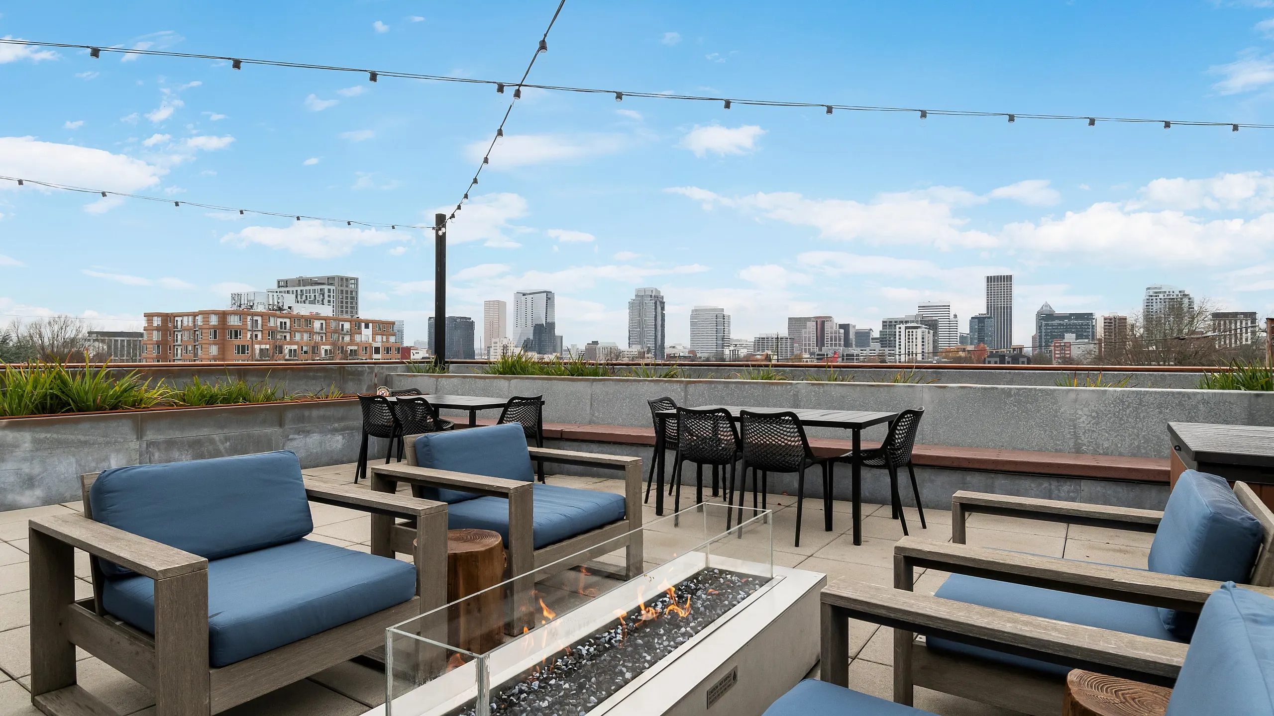 Stunning rooftop patio with modern fire pit, sleek outdoor seating, and breathtaking city skyline view.