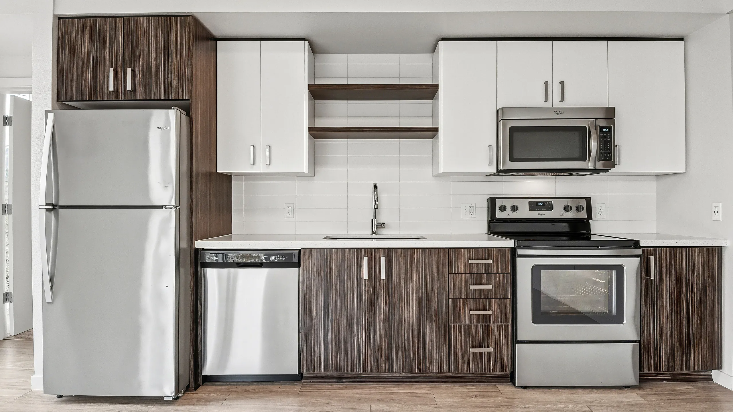 Modern kitchen with stainless steel appliances, sleek cabinetry, and clean white tile backsplash, perfect for contemporary living.