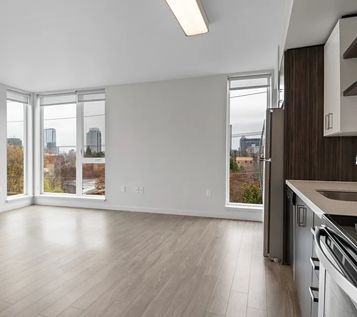 Bright and modern apartment with large windows, sleek kitchen, and stunning city views.