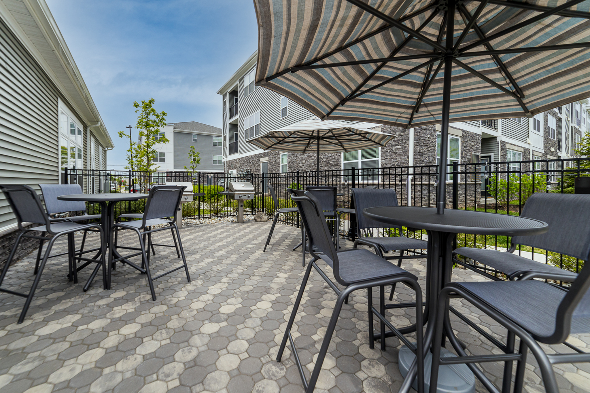 Chic outdoor patio area with modern tables and umbrellas, perfect for relaxing or entertaining in a stylish apartment complex.