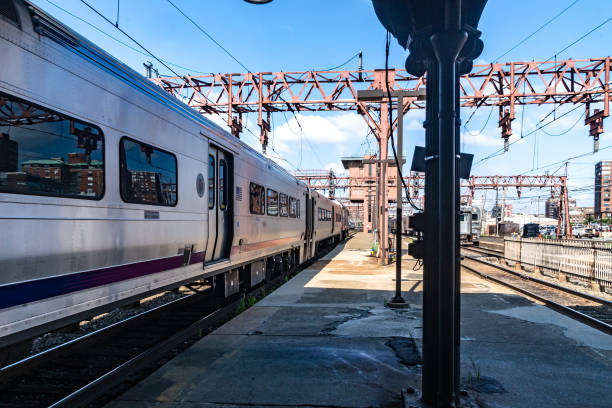 Dynamic railroad scene showcasing a sleek passenger train at a bustling urban platform under a clear blue sky.