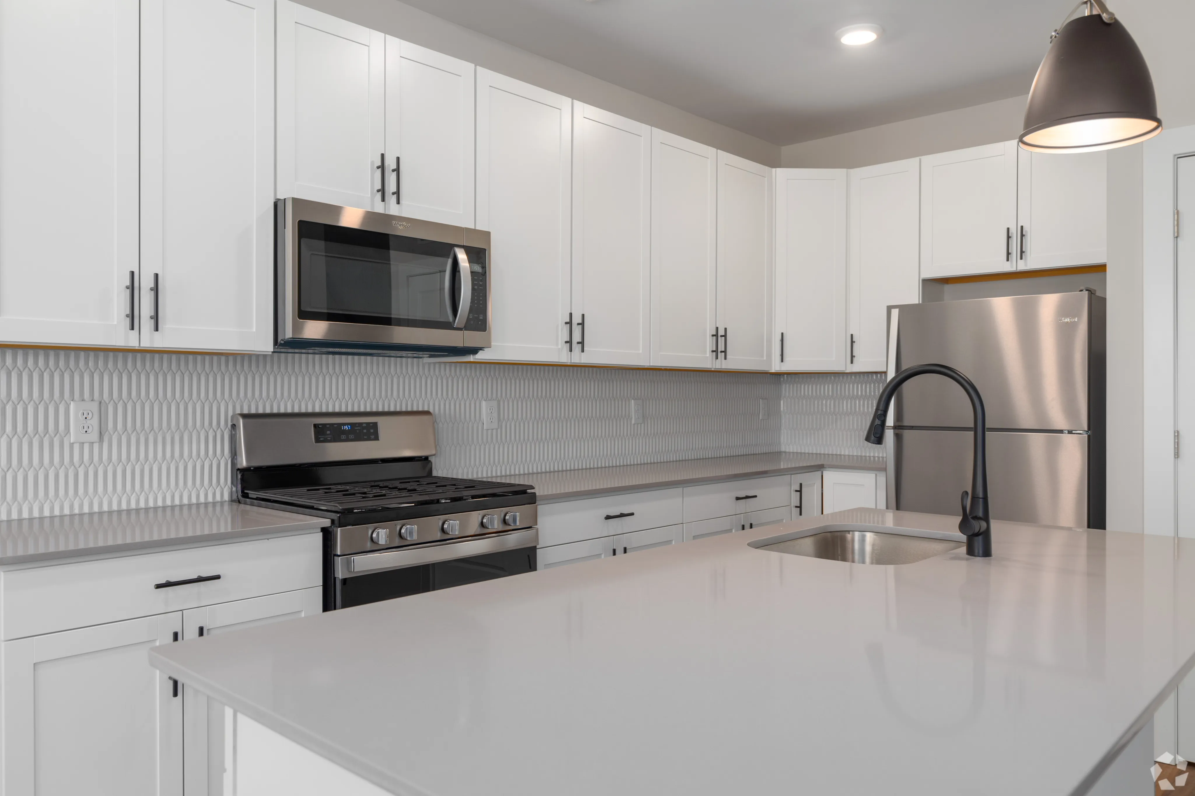 Modern kitchen with sleek white cabinetry, stainless steel appliances, and elegant tile backsplash.