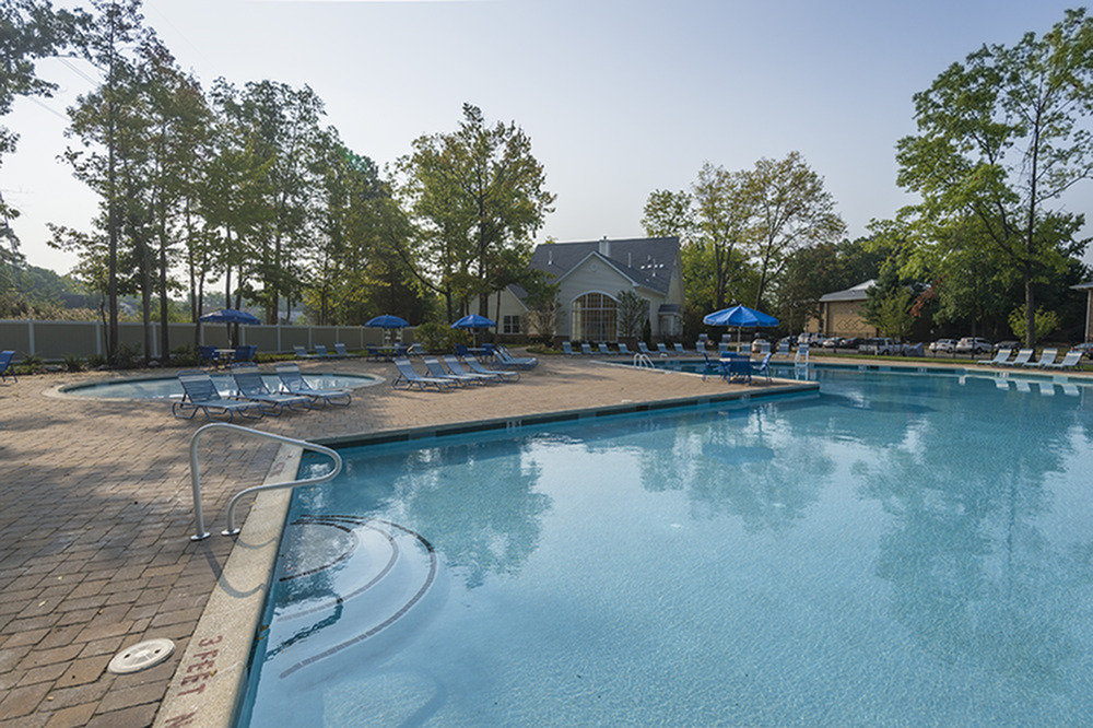 Luxurious outdoor pool area surrounded by lush greenery, featuring elegant lounge chairs and umbrellas for a relaxing experience.