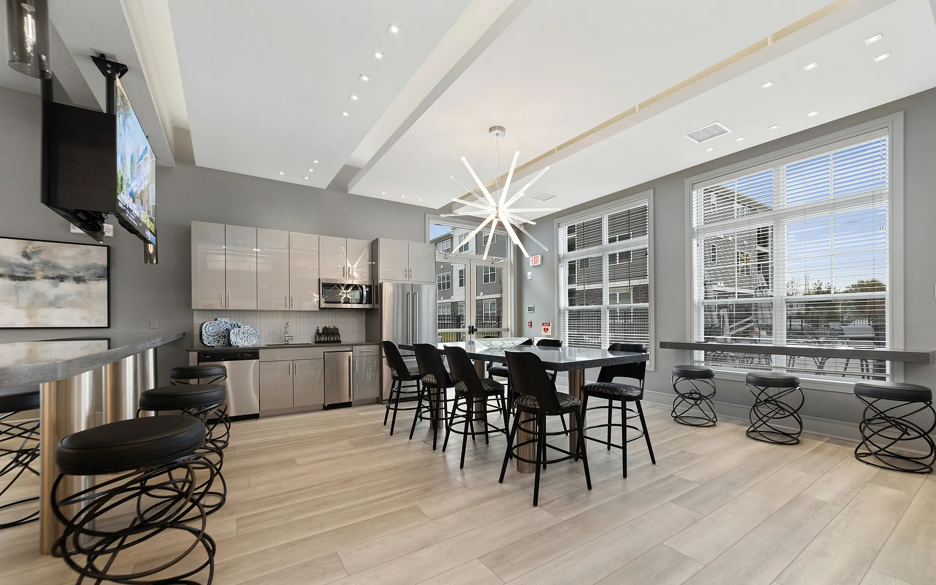 Chic modern kitchen and dining area with sleek cabinetry, stylish bar stools, and elegant lighting, offering a bright and inviting atmosphere.