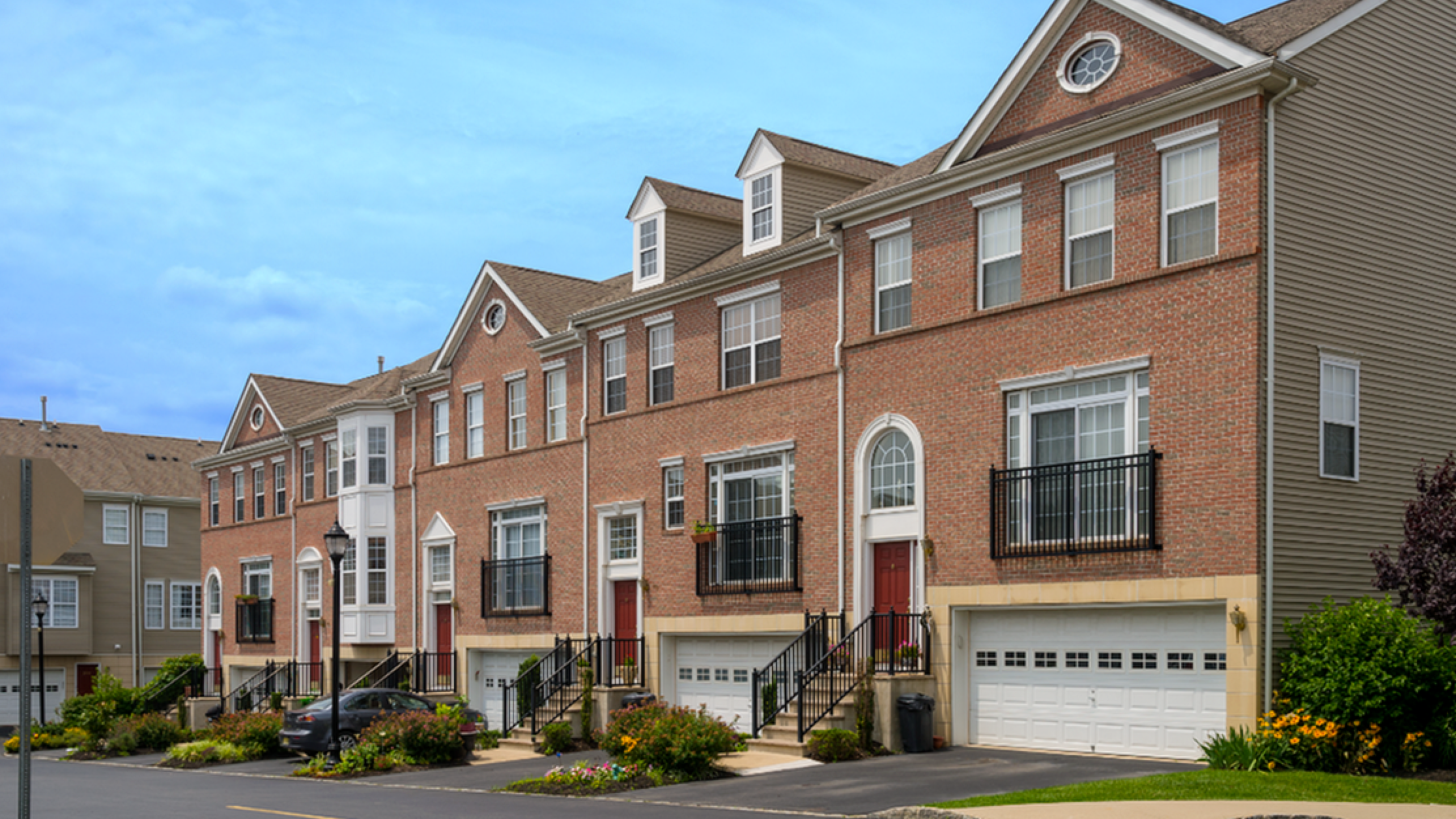 Charming row of brick townhouses with elegant bay windows and landscaped front gardens.