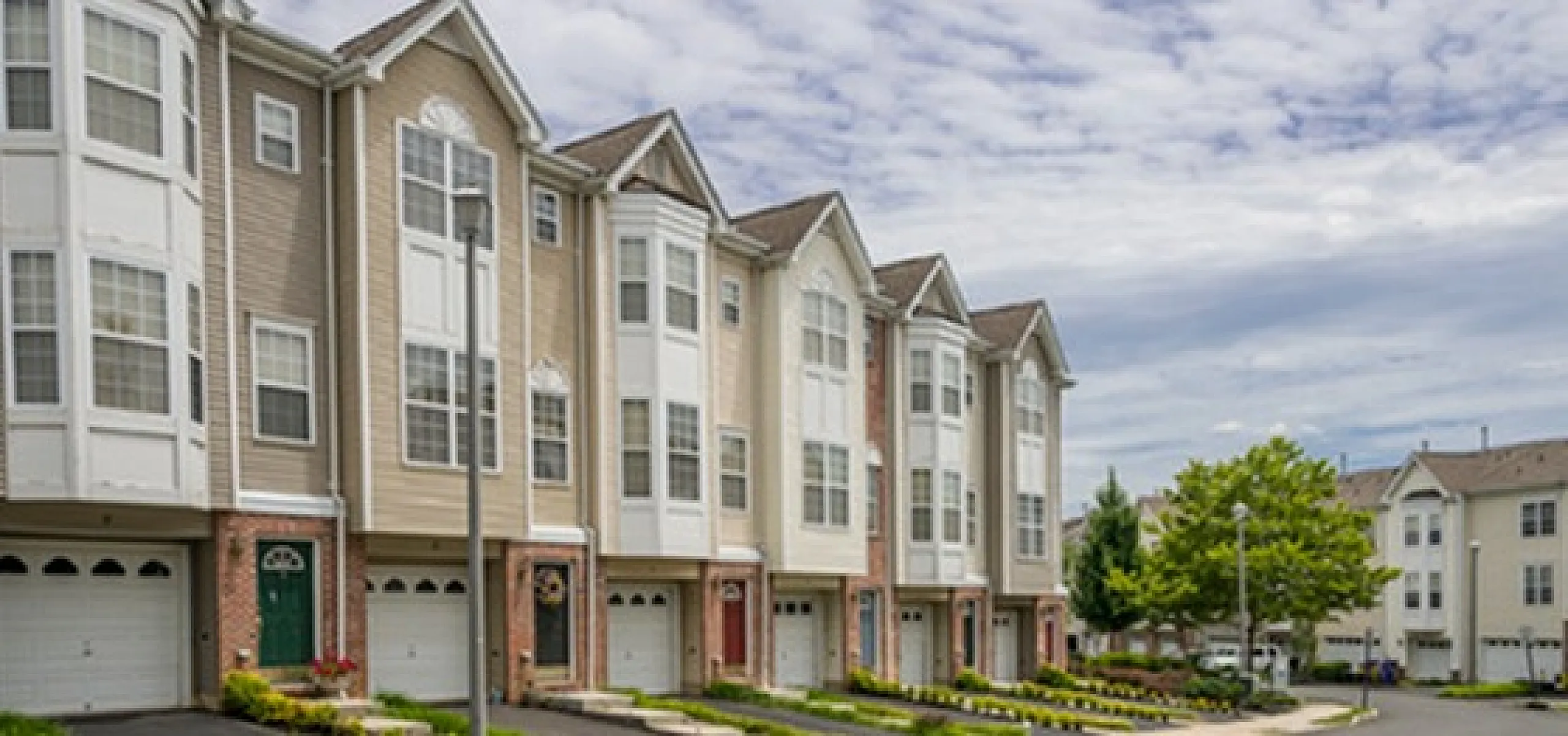 Charming townhouse row with elegant architecture and well-maintained landscaping in a peaceful neighborhood setting.
