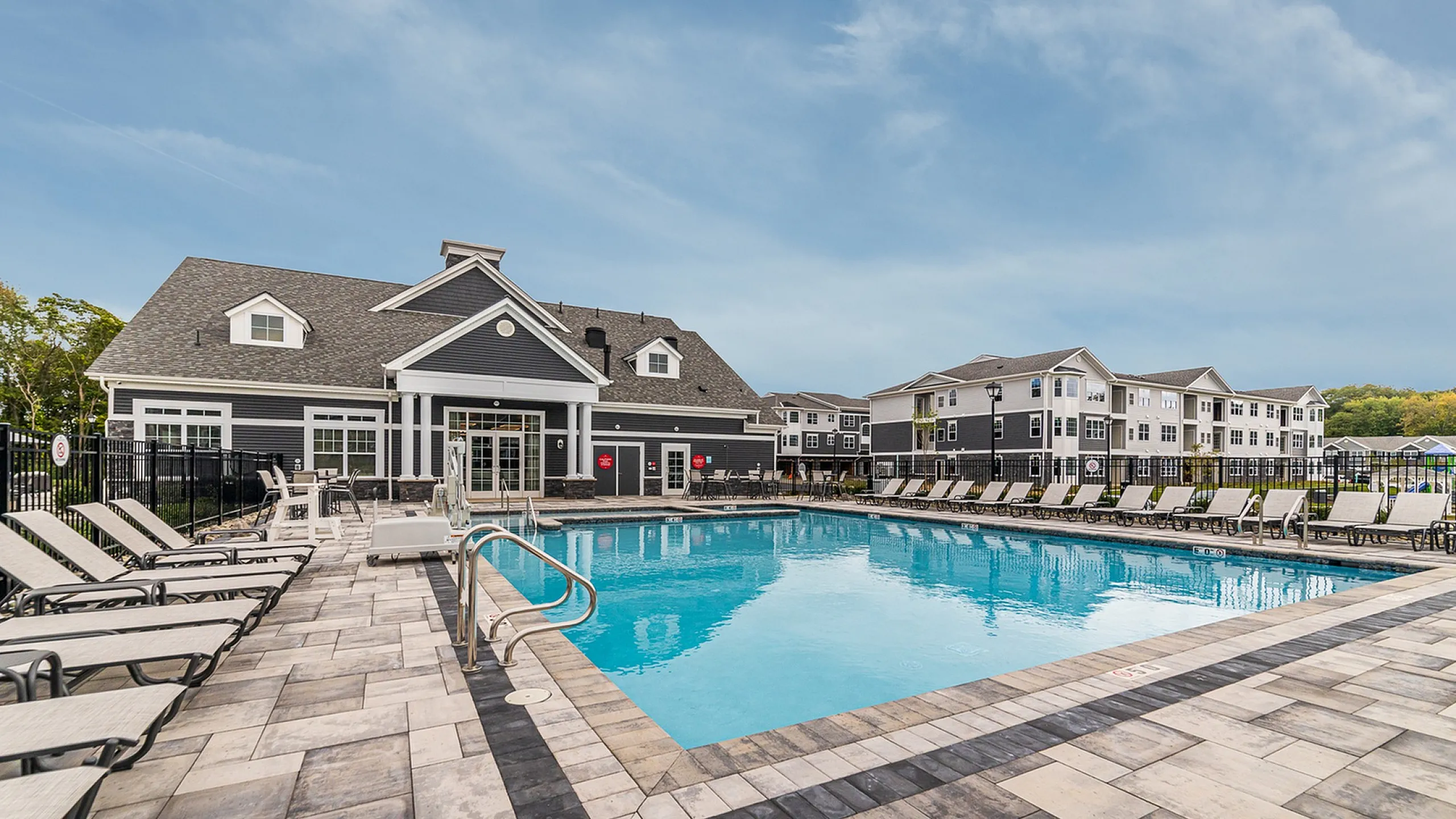 Luxurious apartment complex with a sparkling outdoor pool, surrounded by stylish loungers and elegant architecture, perfect for relaxation and entertainment.