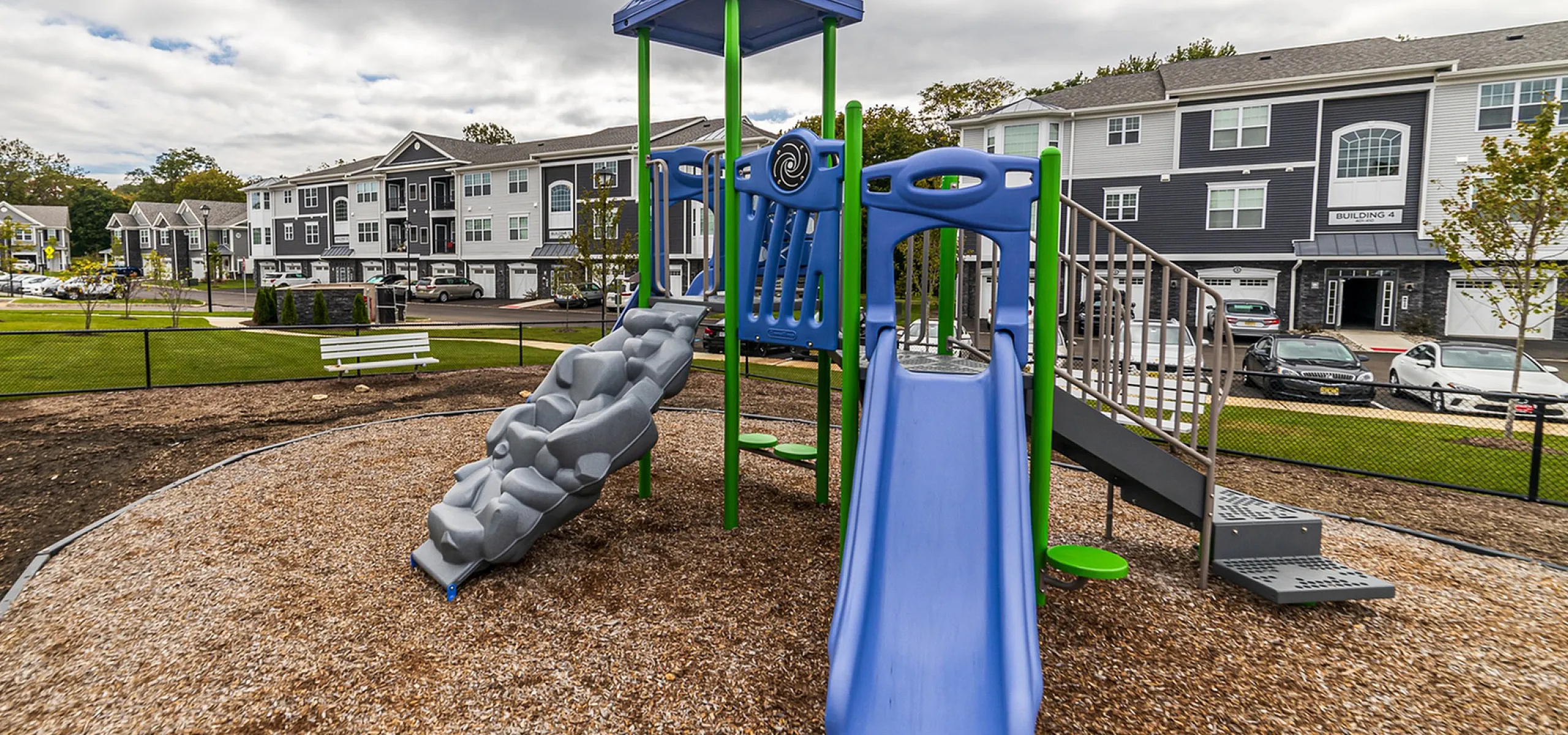 Charming residential area with modern apartments and a colorful playground featuring slides and climbing structures.