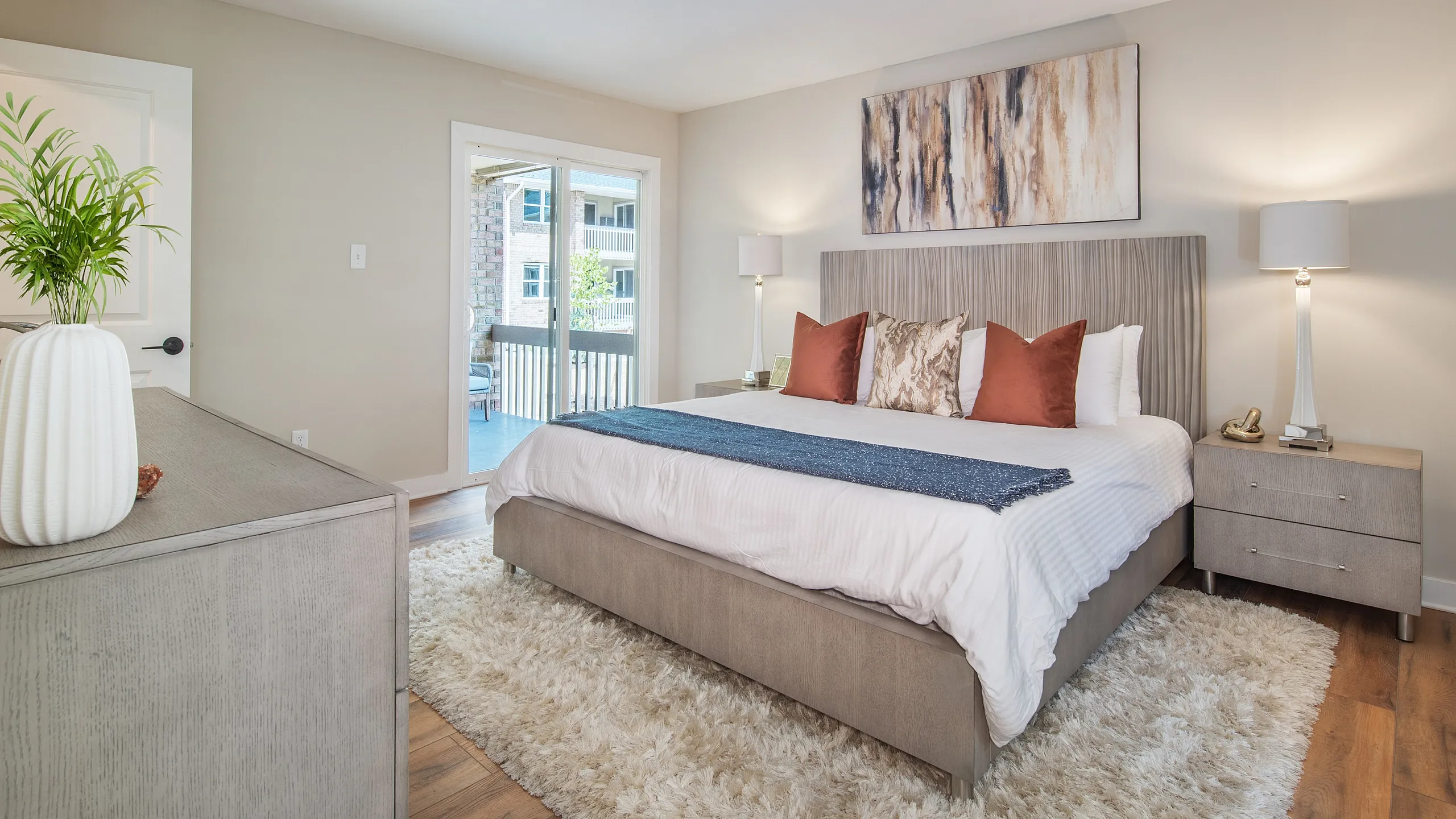 Luxurious bedroom featuring a plush king-sized bed with stylish cushions, elegant bedside lamps, and a serene balcony view.