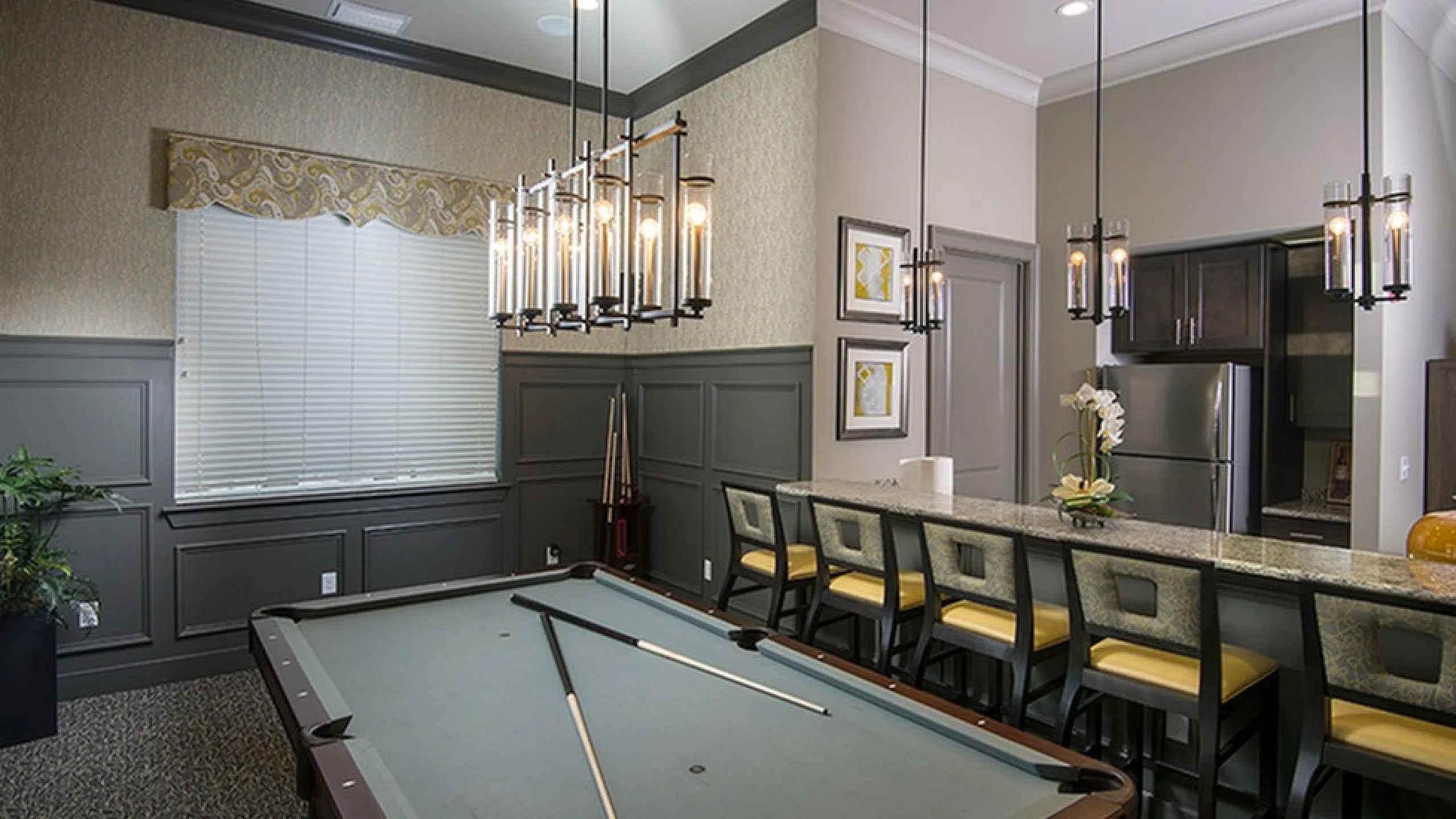 Chic apartment interior featuring a stylish billiard room with modern pendant lighting and a sleek kitchen bar with elegant seating.