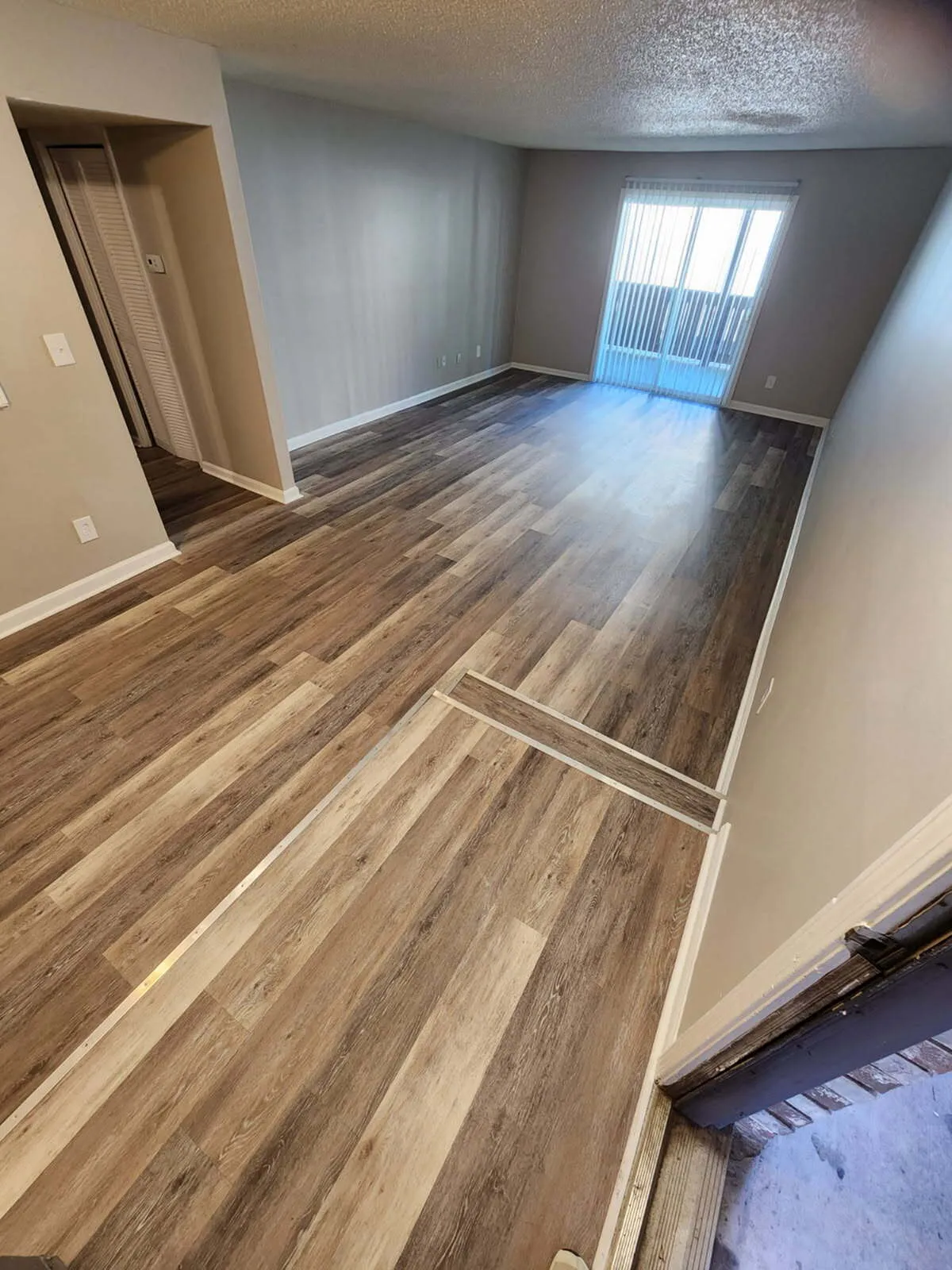 Chic living area with elegant wood flooring and natural light from sliding doors, perfect for modern comfort.