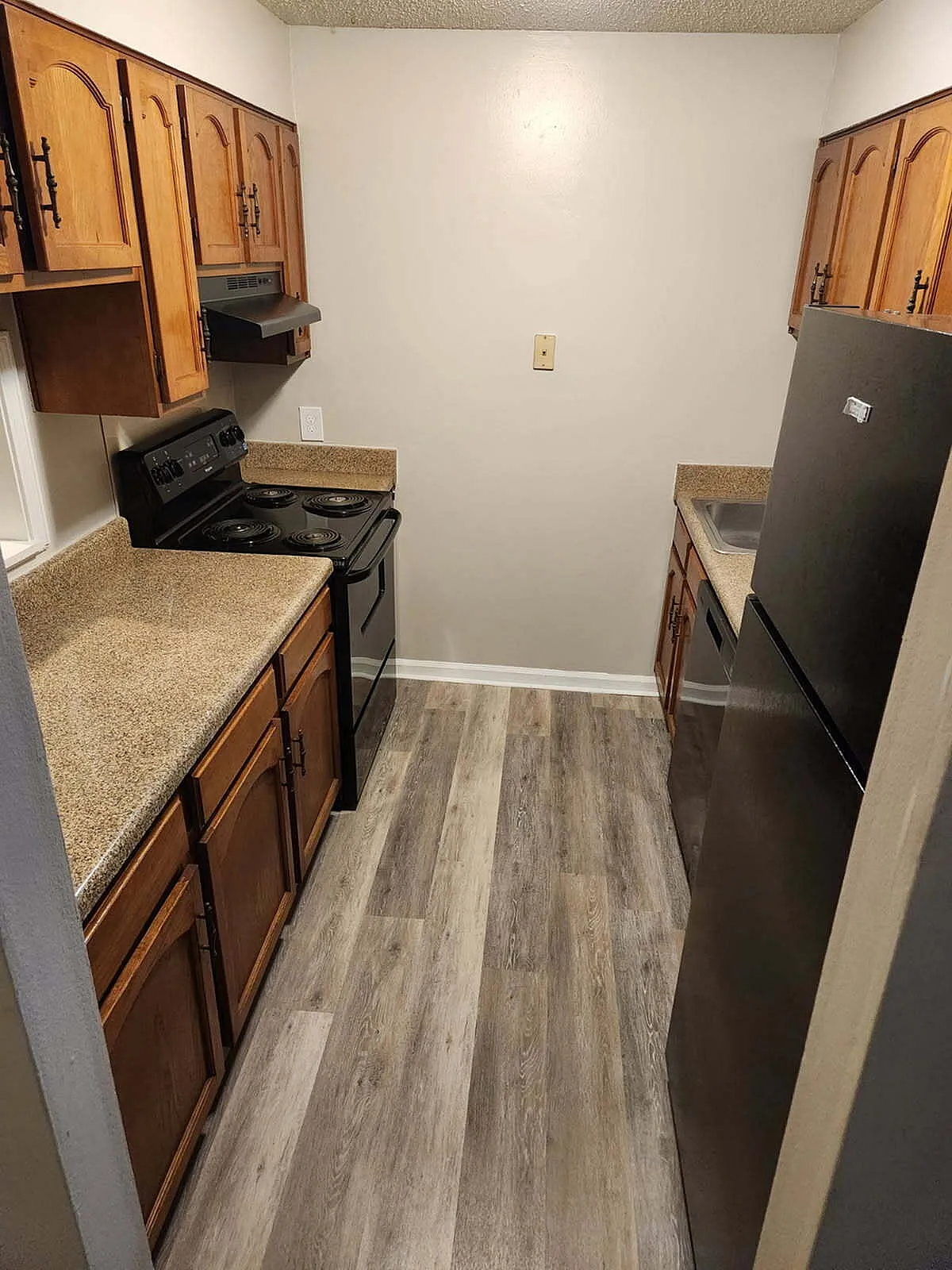 Cozy kitchen with warm wooden cabinets, sleek black appliances, and elegant laminate flooring, perfect for culinary creativity.