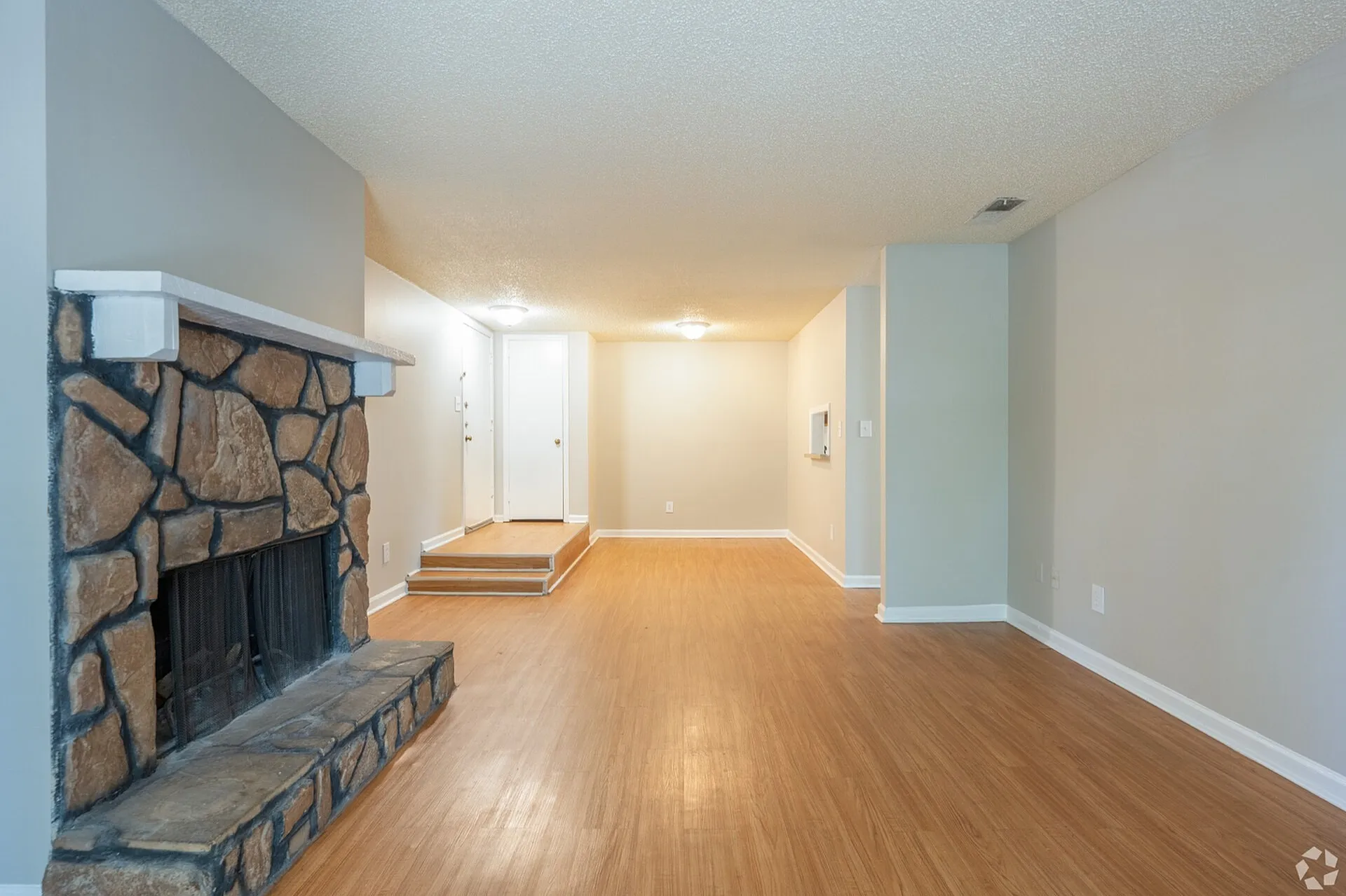 Inviting living room with cozy stone fireplace and elegant wood flooring, perfect for relaxing or entertaining.