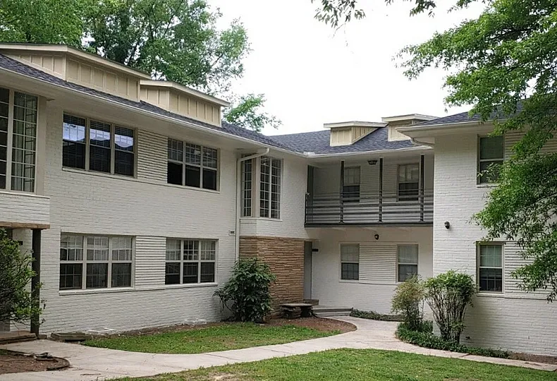 Charming apartment complex with a modern two-story design, surrounded by lush greenery and offering spacious balconies.