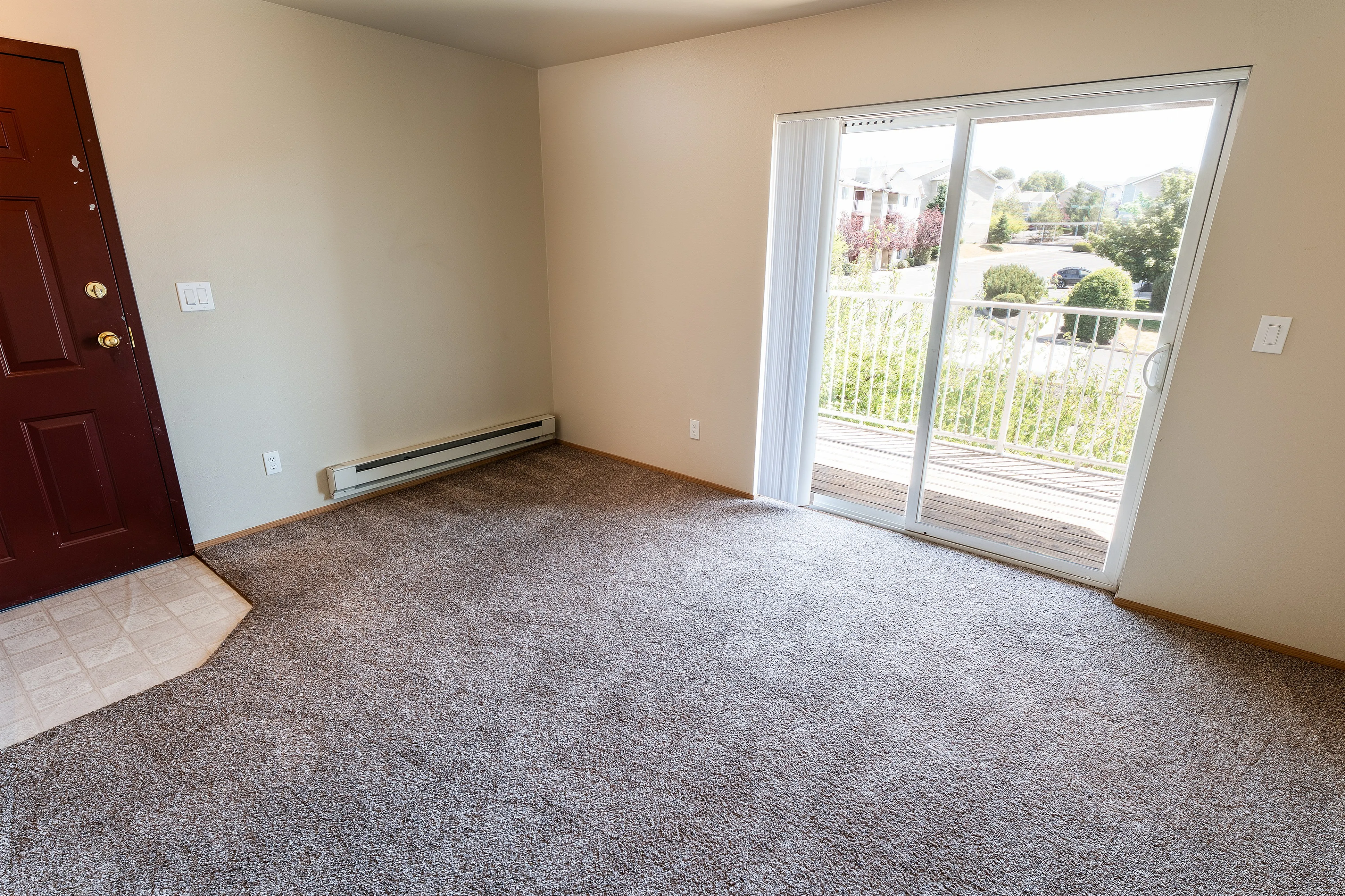 Inviting living room with plush carpeting and abundant natural light from large sliding glass doors leading to a balcony with scenic views.