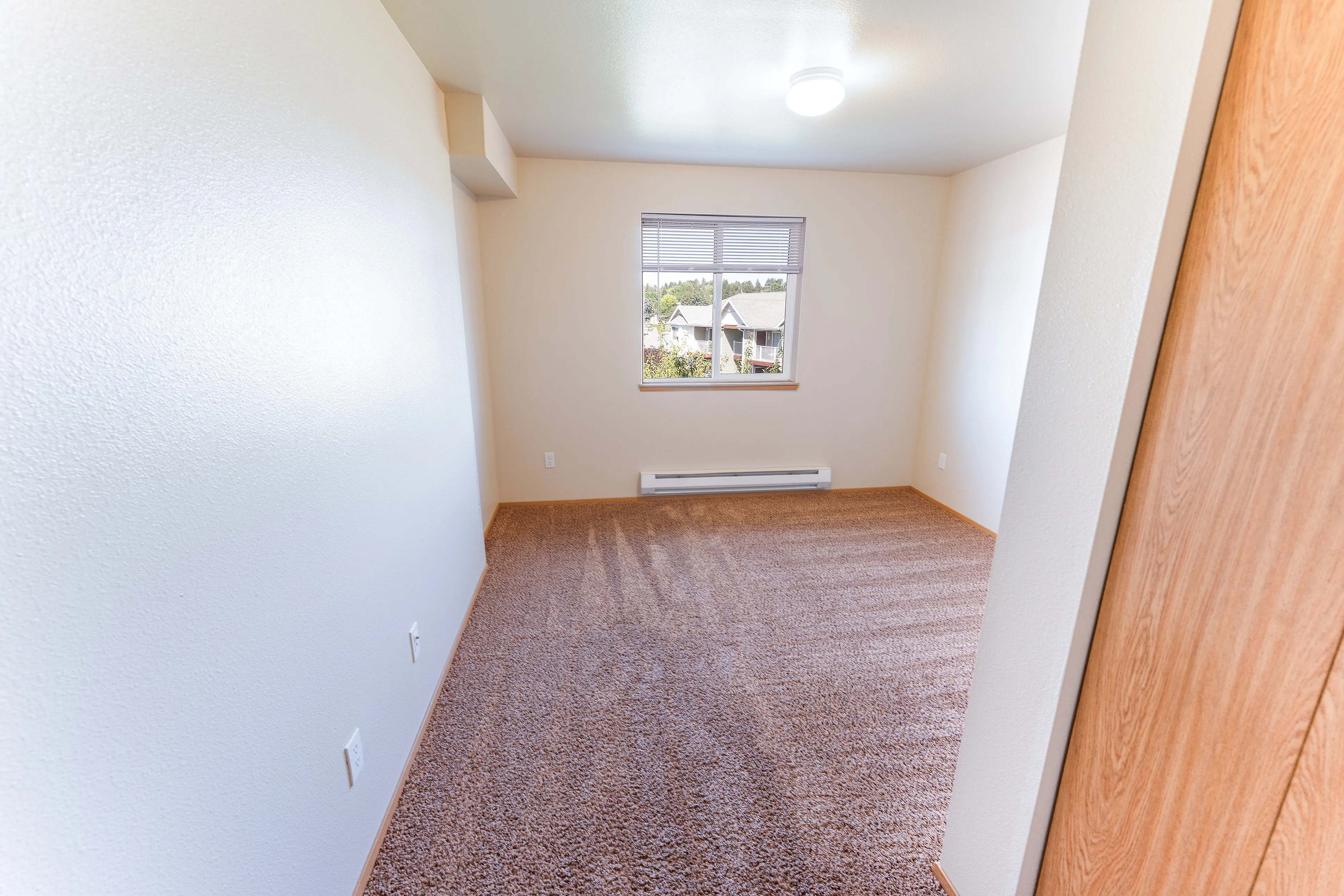 Bright and inviting bedroom with plush carpet and a large window offering scenic views, perfect for relaxation.