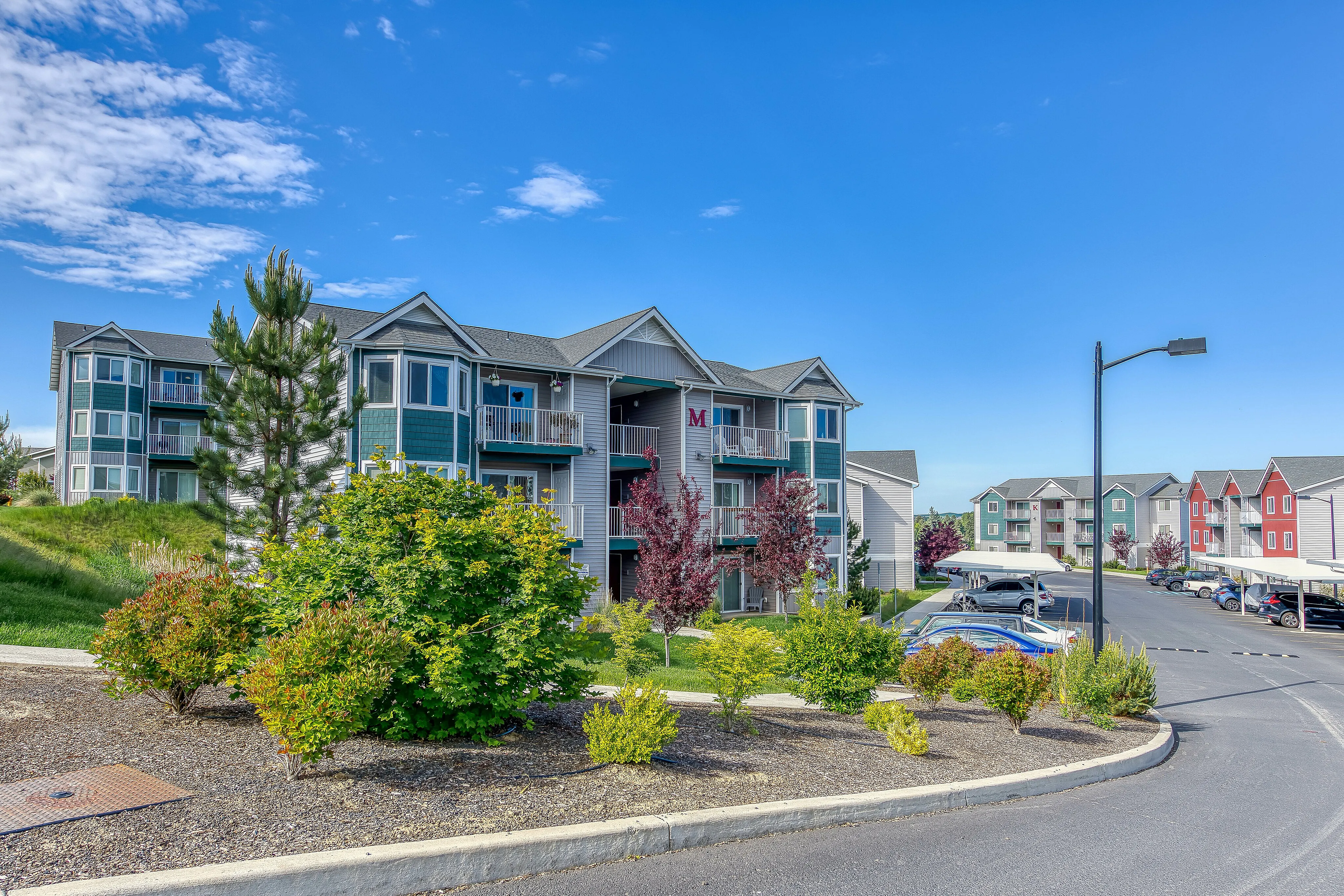 Charming apartment complex featuring modern design with lush landscaping and vibrant exterior colors.