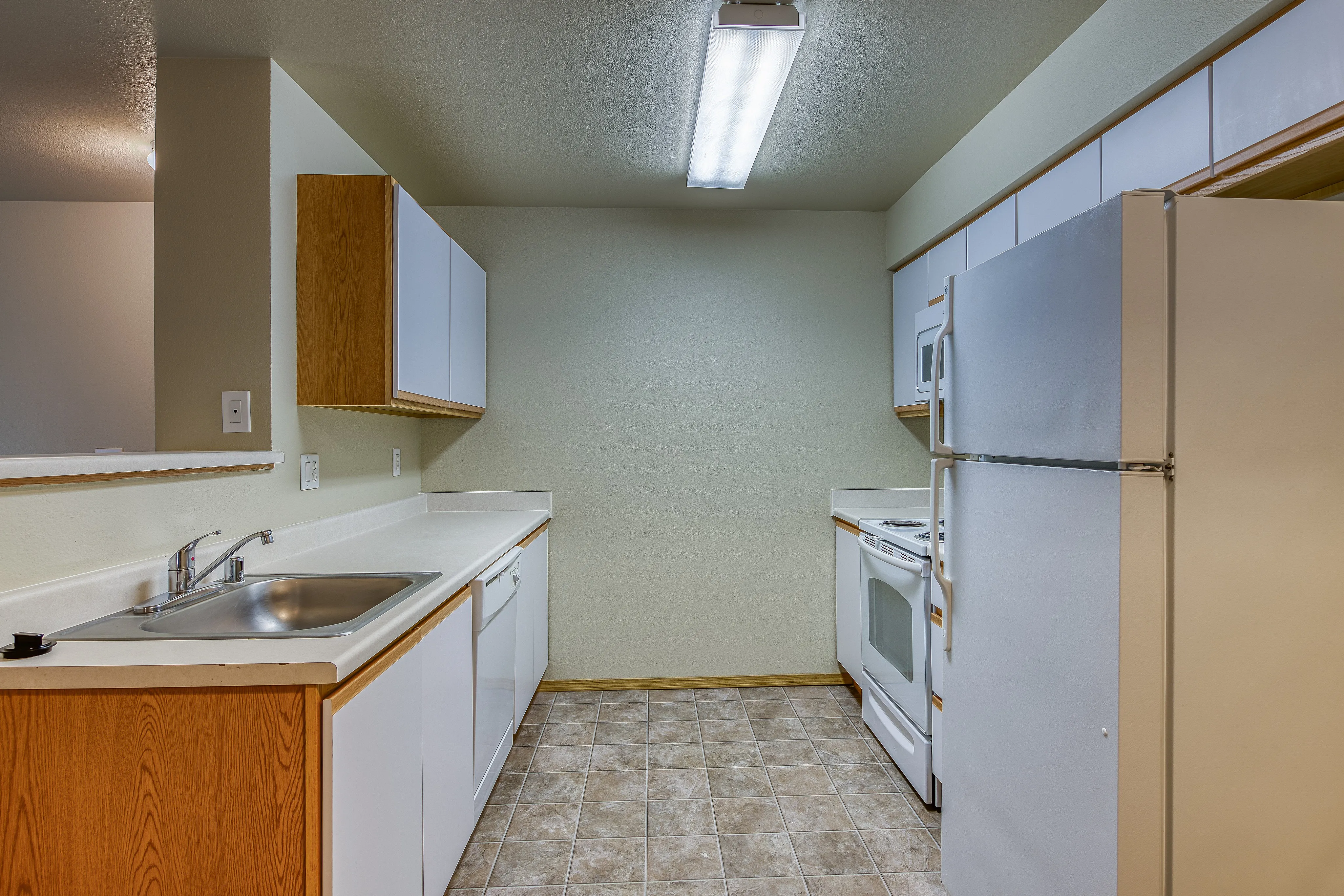 Modern kitchen with sleek wooden cabinets, stainless steel sink, and spacious countertops, ideal for culinary enthusiasts.
