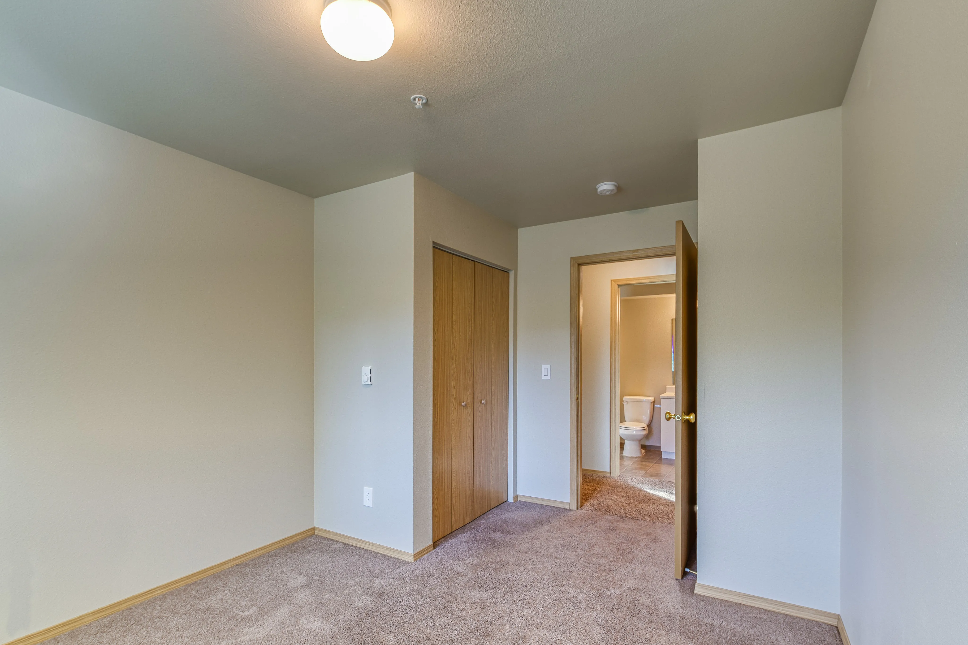 Inviting bedroom with neutral tones, cozy carpet, and ample closet space leading to a private bathroom.