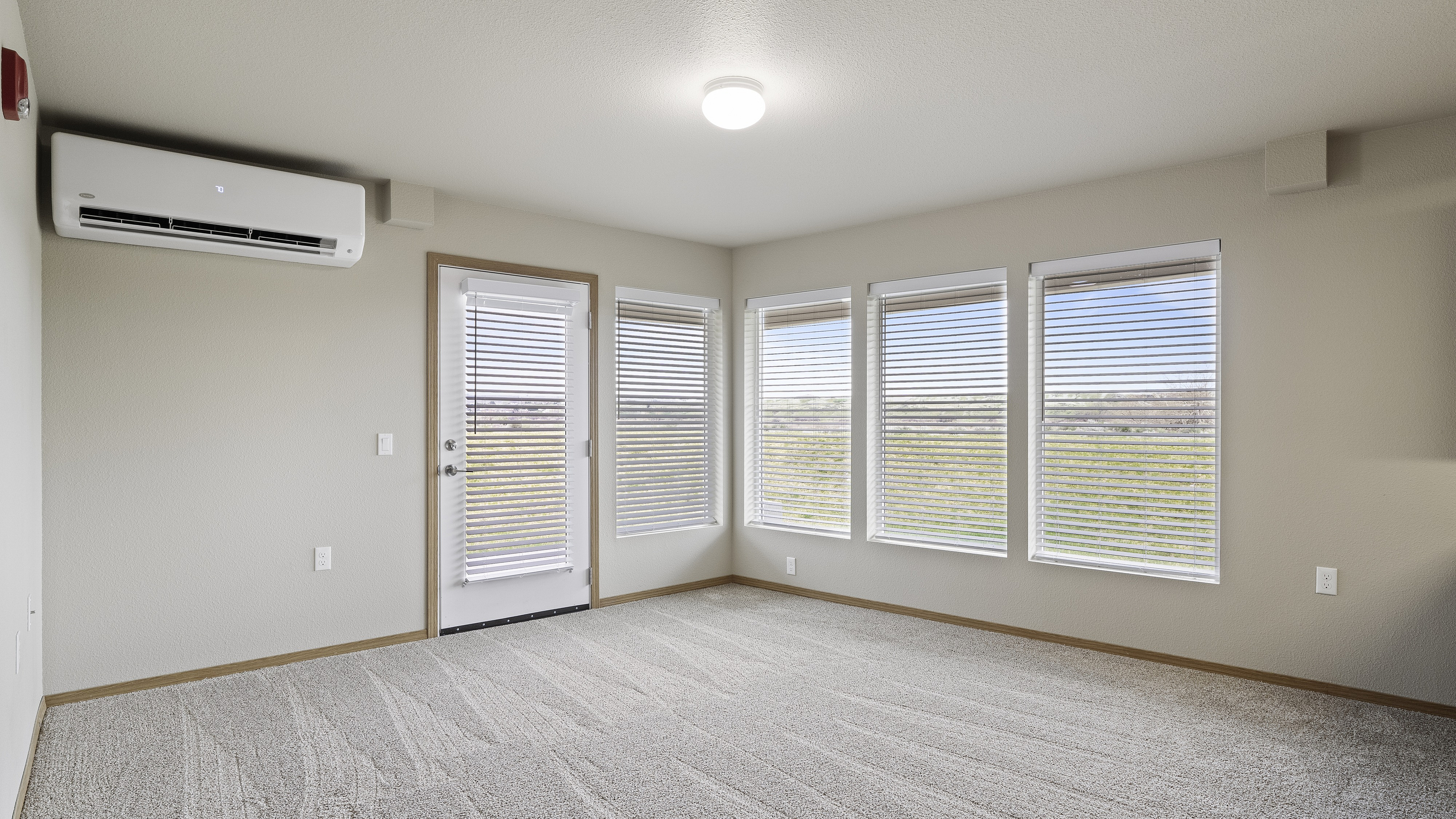 Bright, inviting room with large windows, plush carpet, and modern air conditioning, perfect for relaxation.