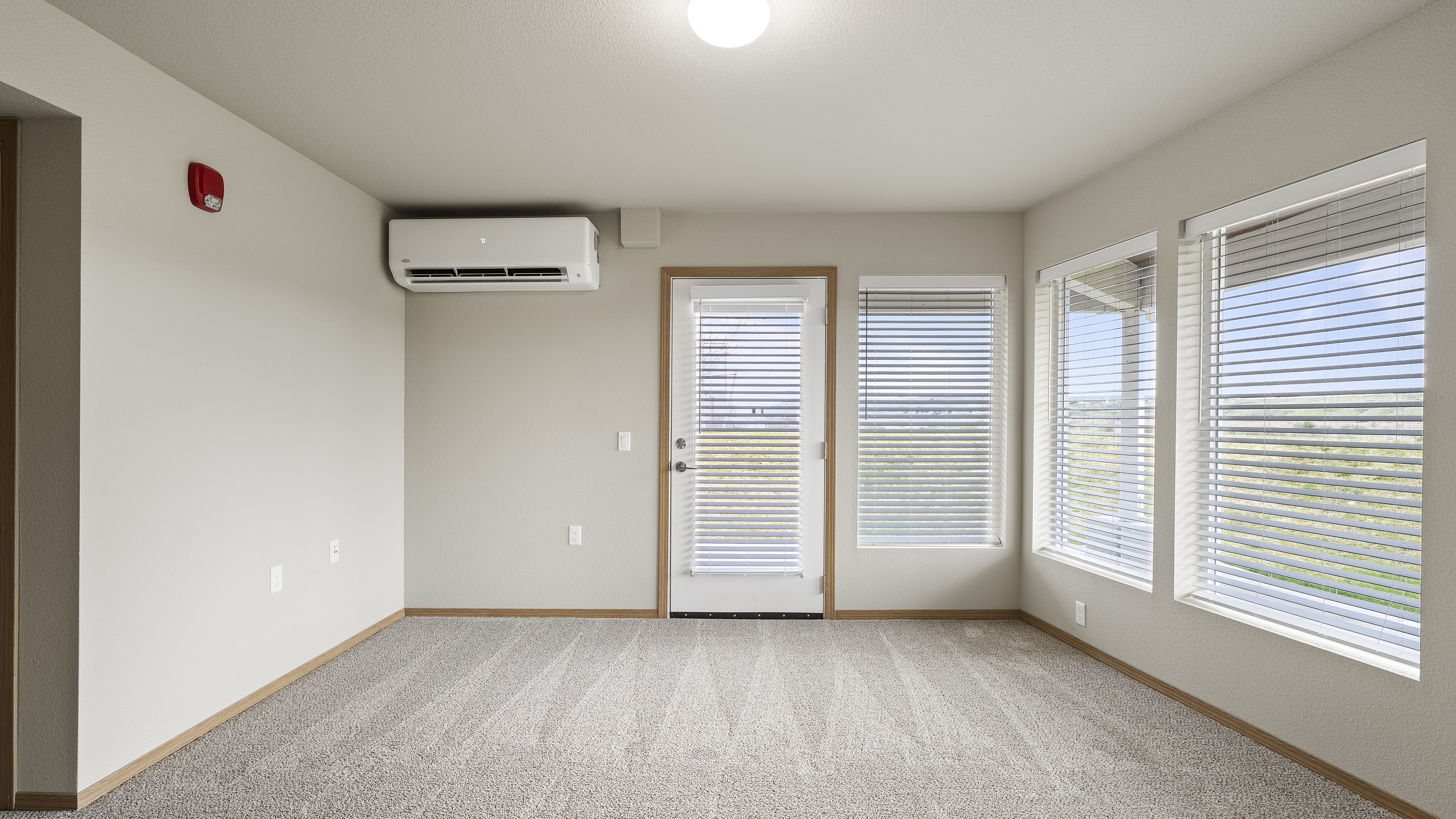 Bright and airy room with large windows, plush carpet, and modern air conditioning unit offering scenic views.