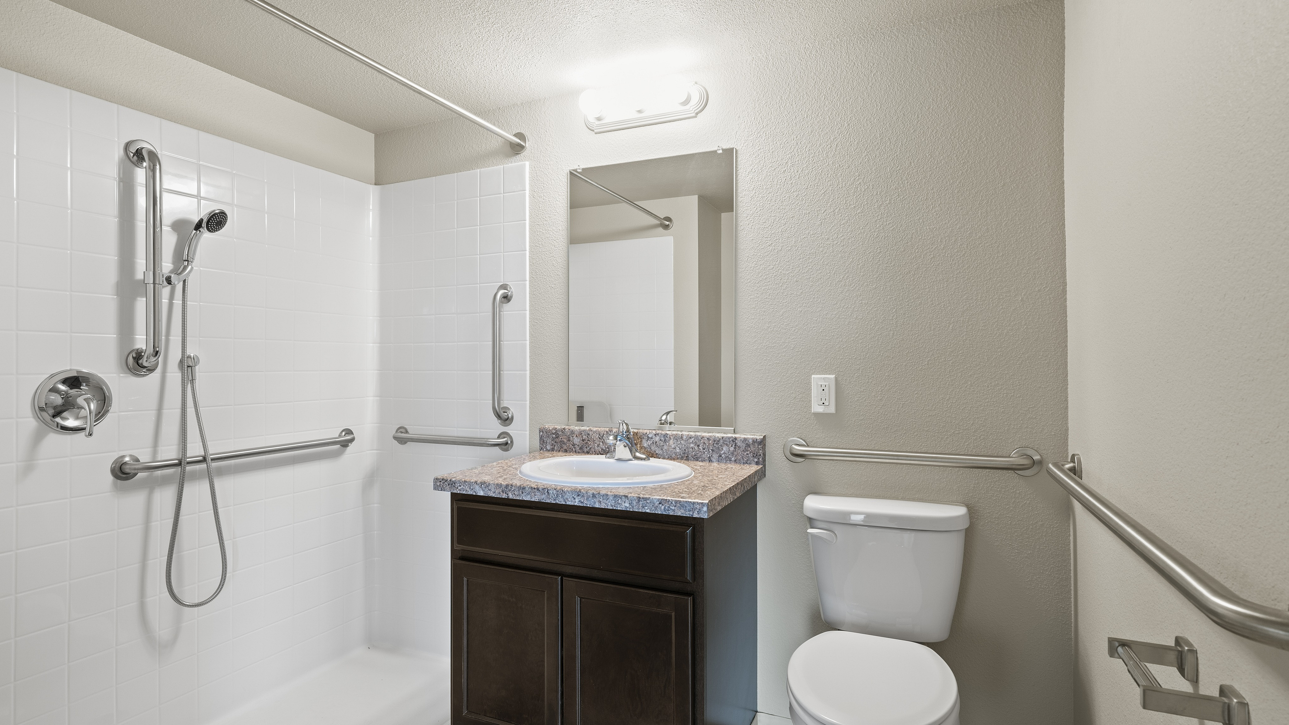 Bright and modern bathroom with accessible design featuring elegant fixtures, a spacious vanity, and convenient grab bars.