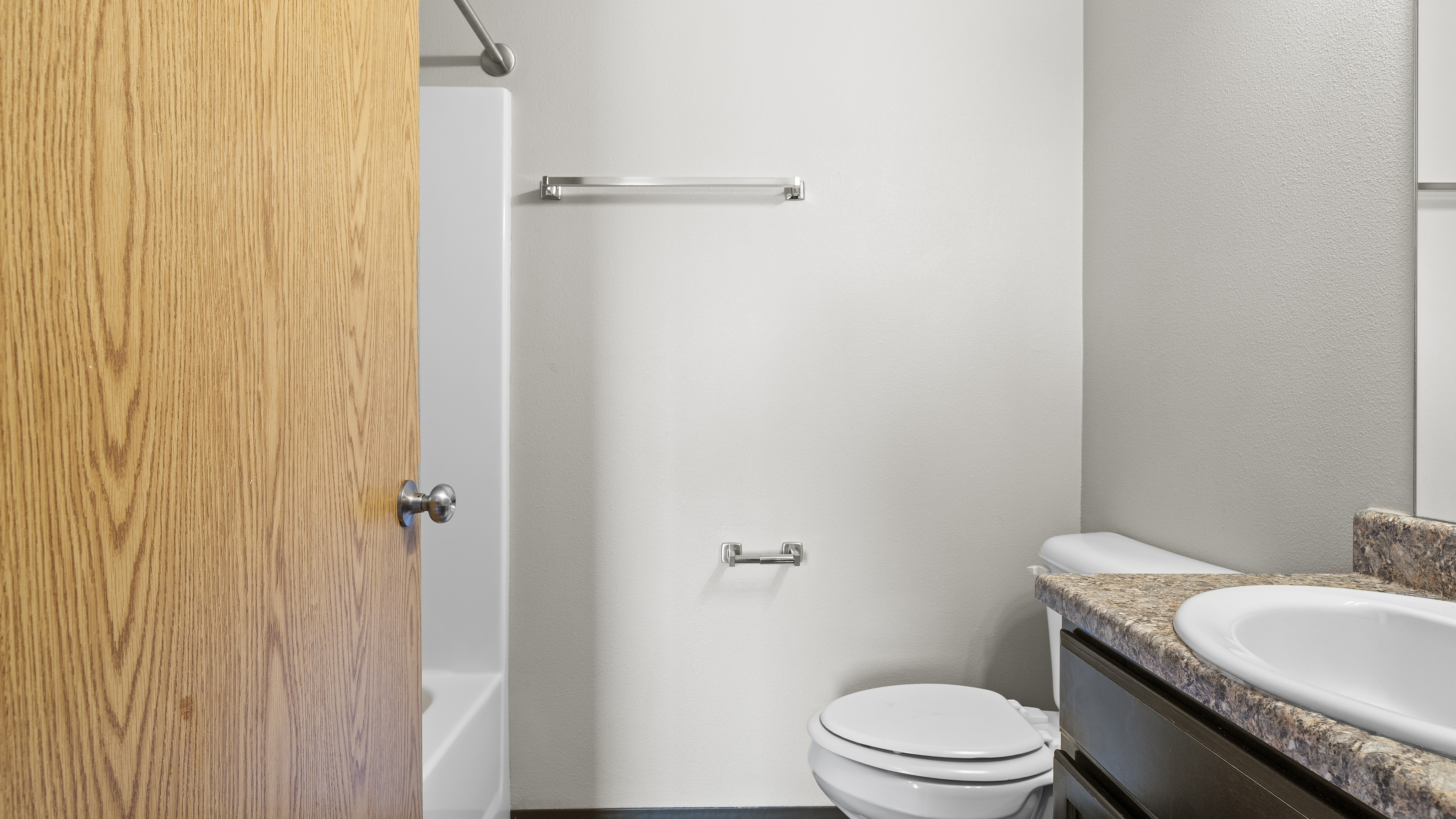 Modern bathroom with elegant granite countertop, sleek fixtures, and a cozy bathtub, perfect for relaxation.