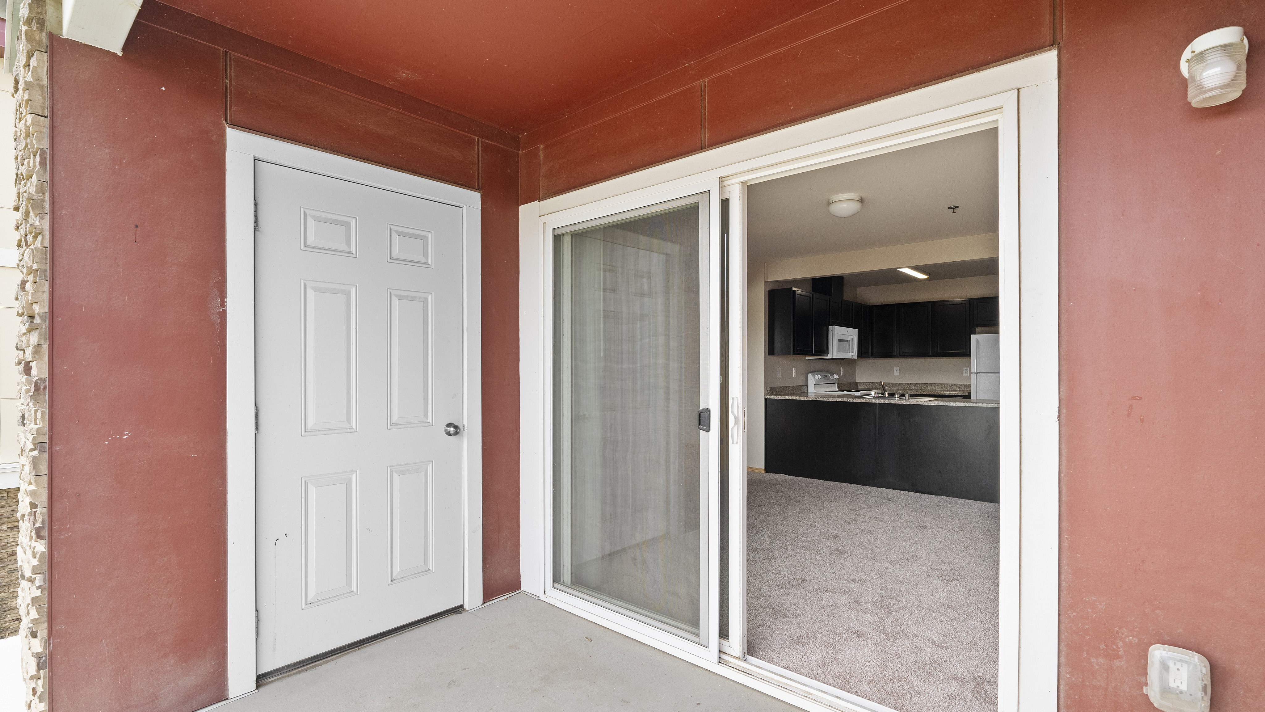 Inviting apartment patio with sliding glass door leading to a modern kitchen and cozy carpeted living area.