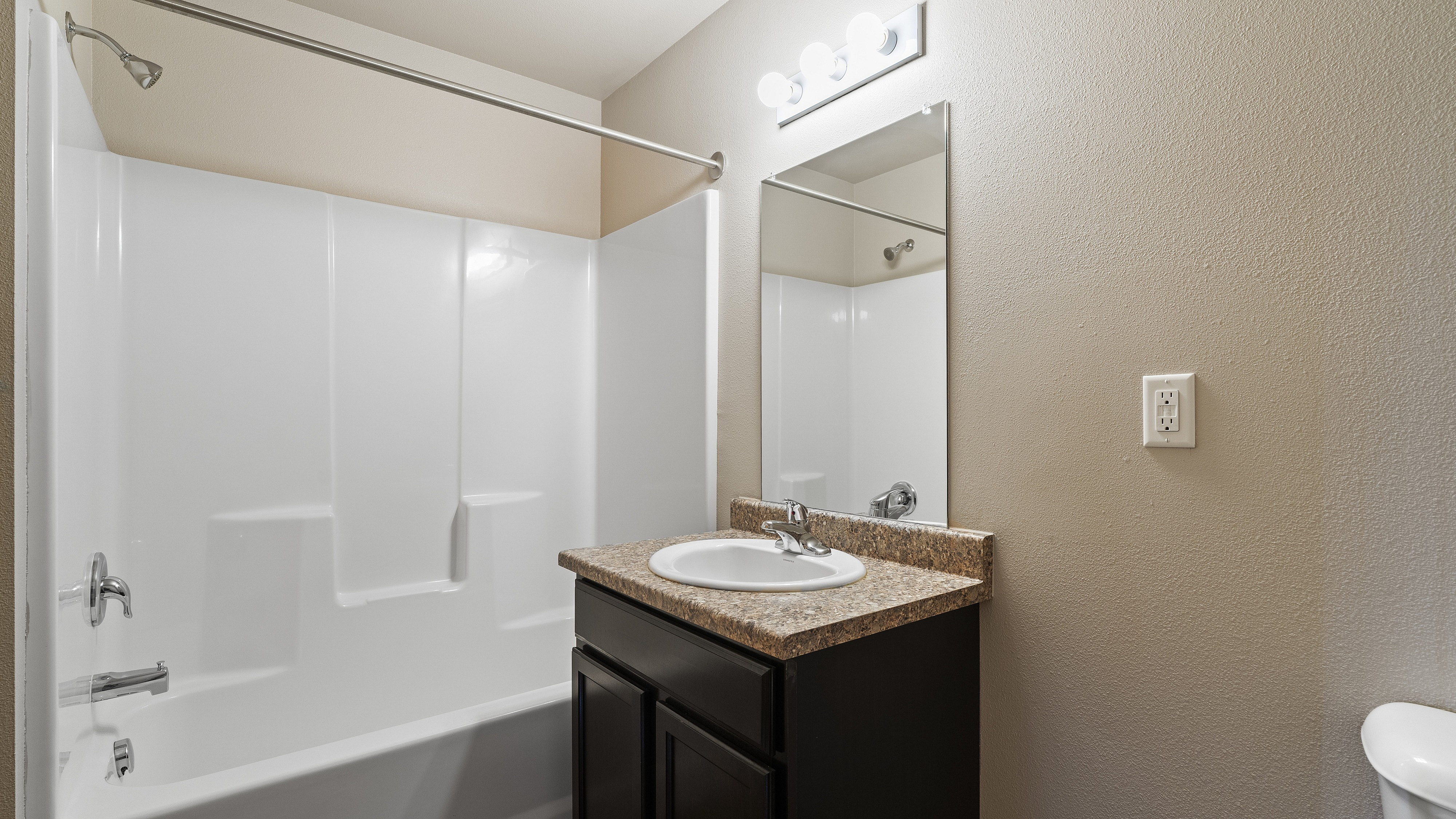 Modern bathroom with sleek fixtures, elegant countertop, and pristine bathtub, offering a serene and relaxing space.