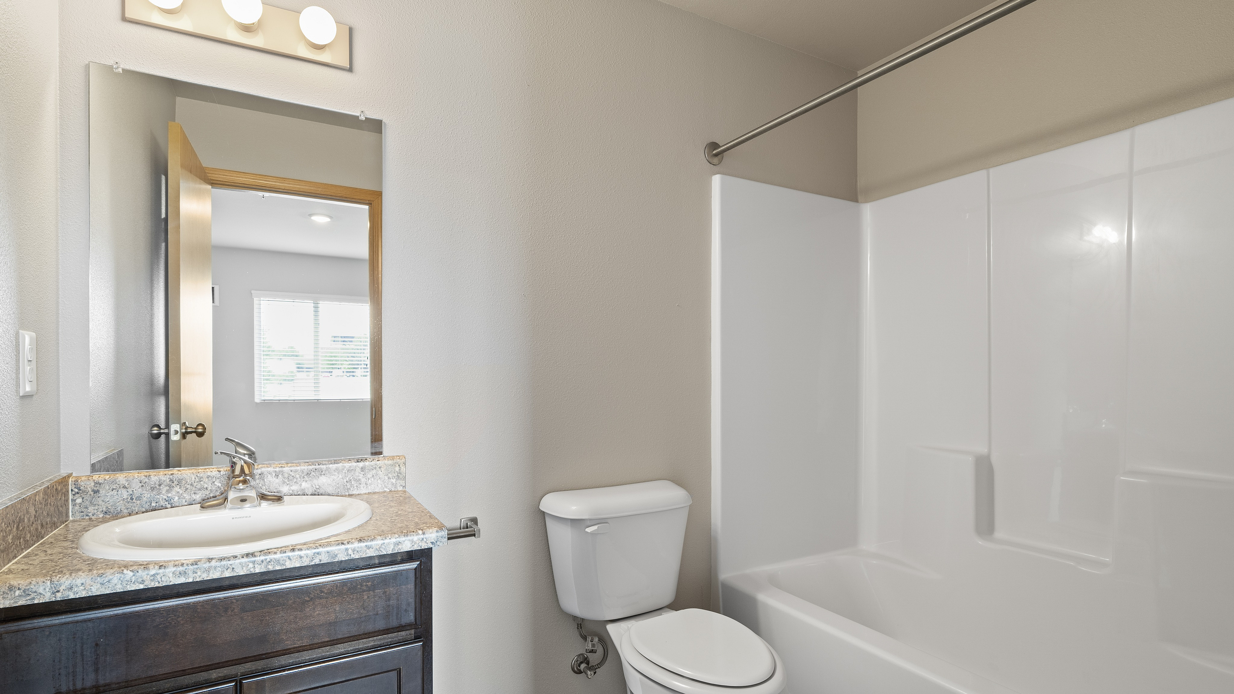Bright and modern bathroom featuring a sleek vanity, elegant countertop, and a pristine bathtub.