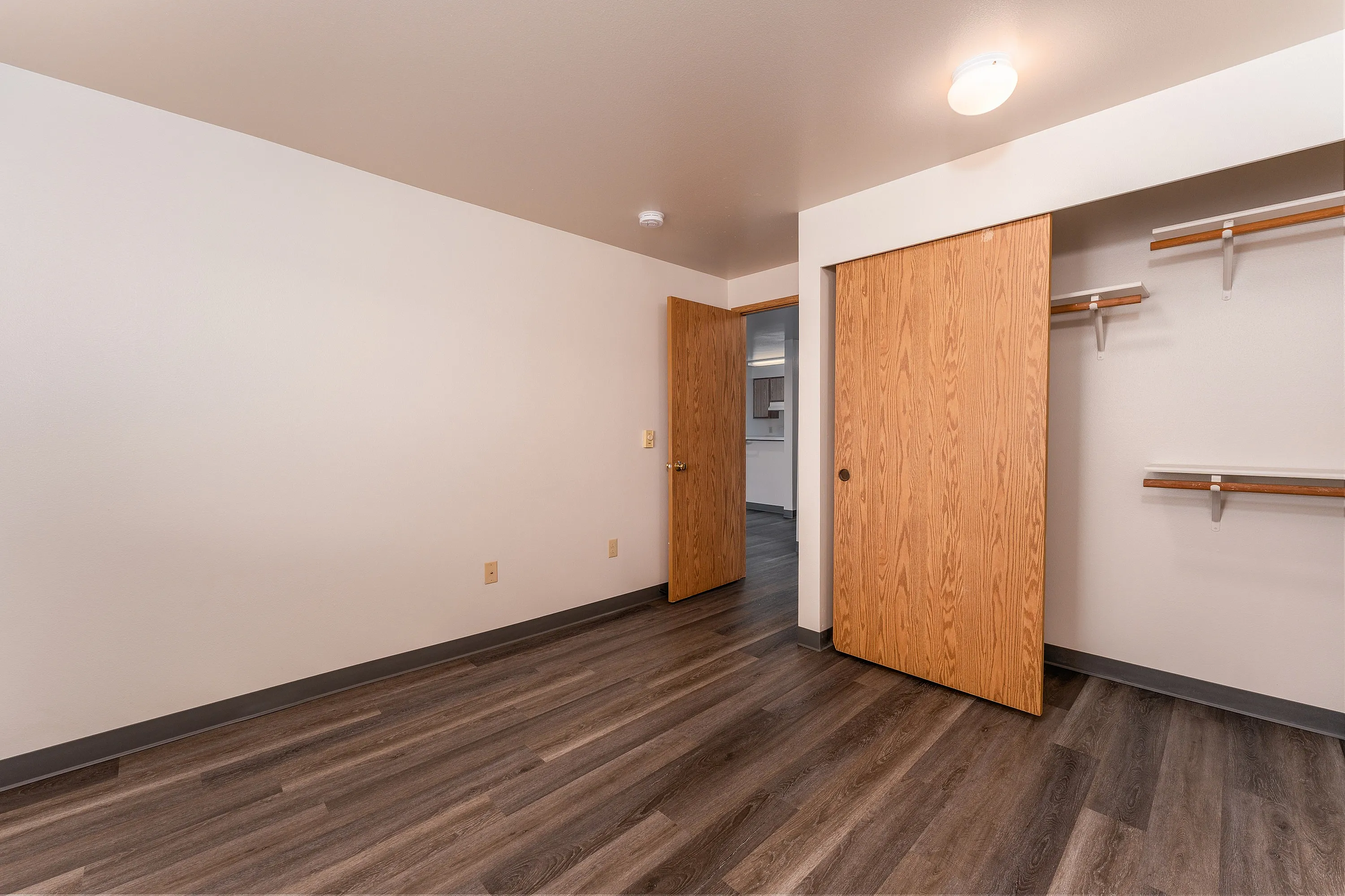 Bright and welcoming bedroom with sleek hardwood flooring and ample closet space, perfect for modern living.