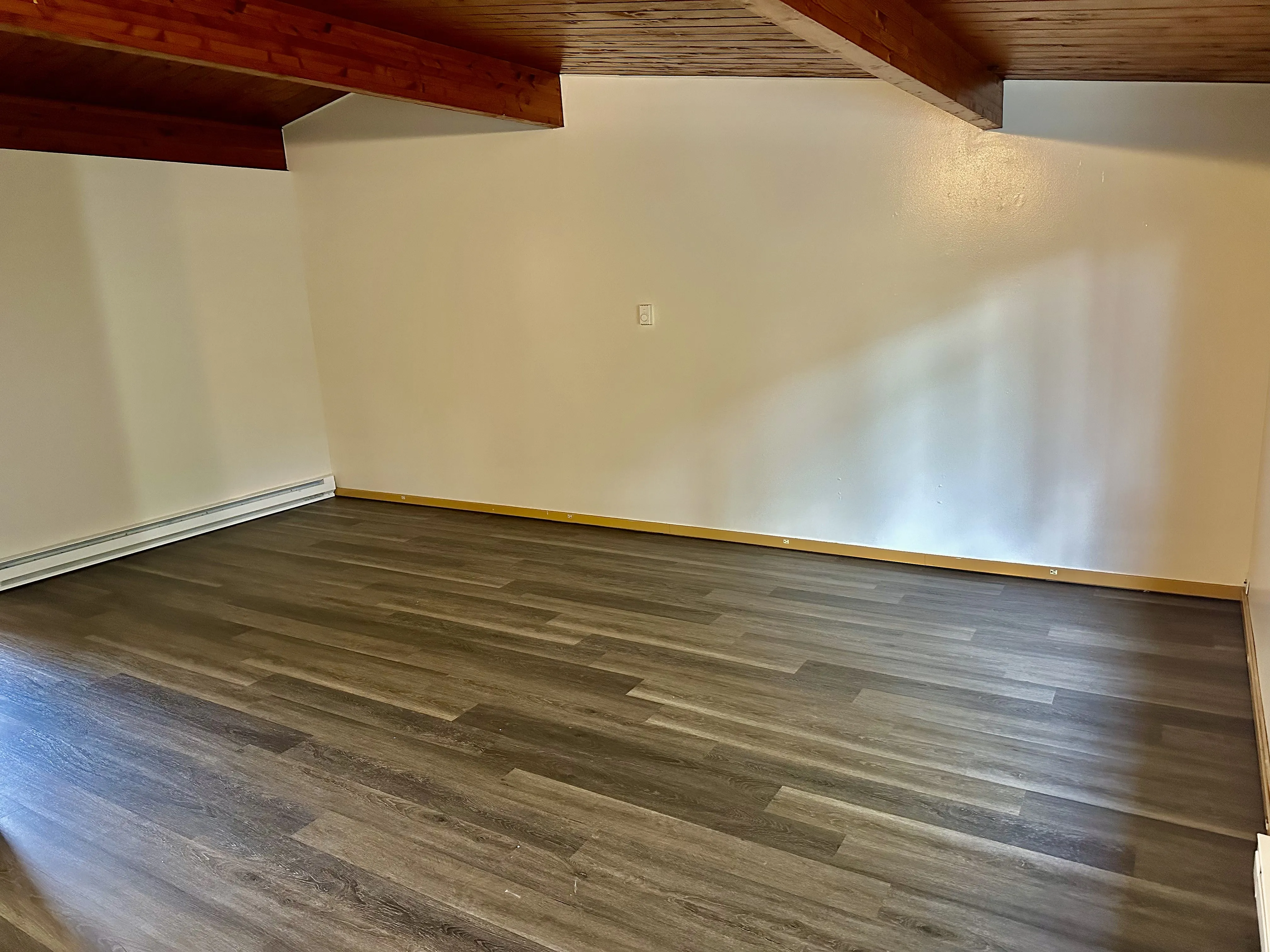 Inviting room with elegant wooden flooring and a charming wood-beamed ceiling, perfect for a cozy retreat.