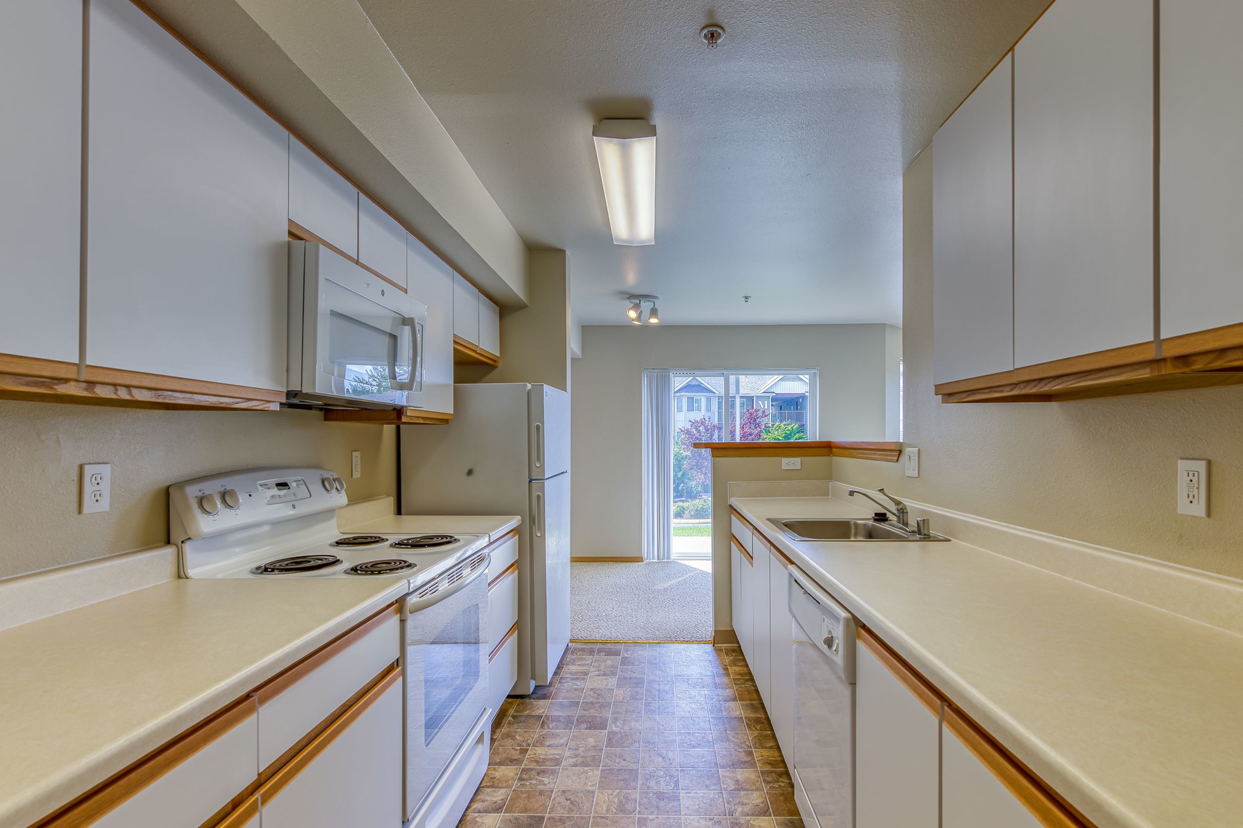 Bright, modern kitchen with sleek white cabinets, spacious countertops, and natural light streaming in through large windows.