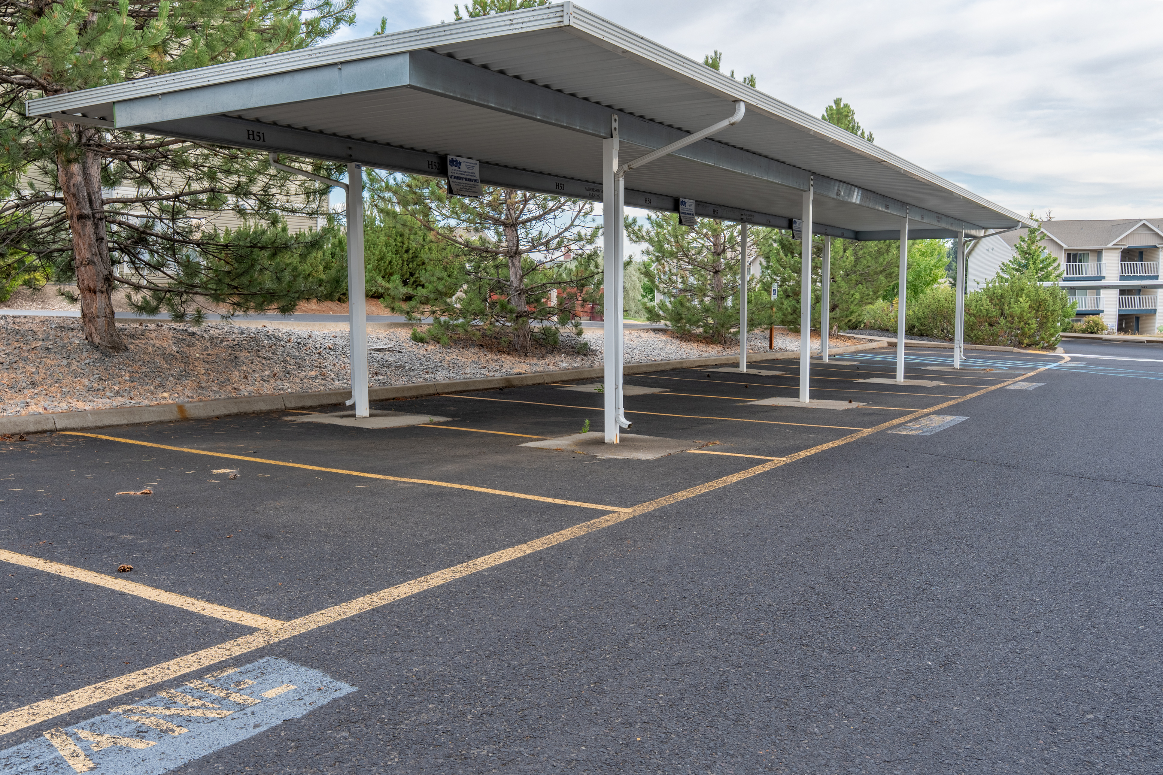 Welcoming covered parking area surrounded by greenery, perfect for easy, protected vehicle access in a tranquil setting.