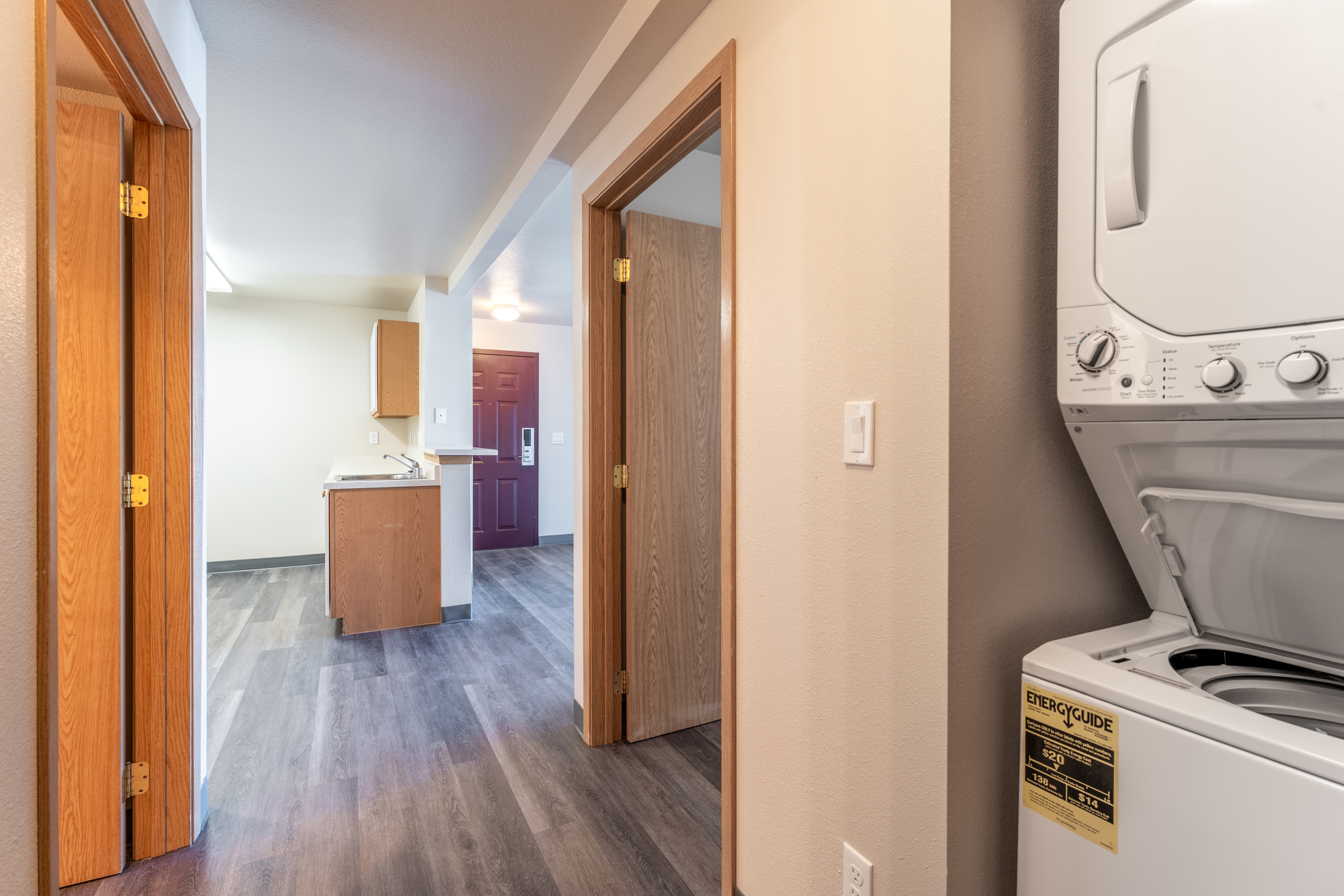 Inviting hallway leading to a bright kitchen with hardwood floors and an in-unit washer and dryer.