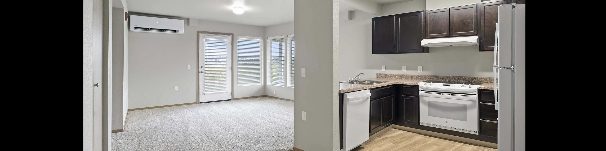Modern apartment interior featuring a sleek kitchen with dark wood cabinets, bright living area with large windows, and elegant flooring.