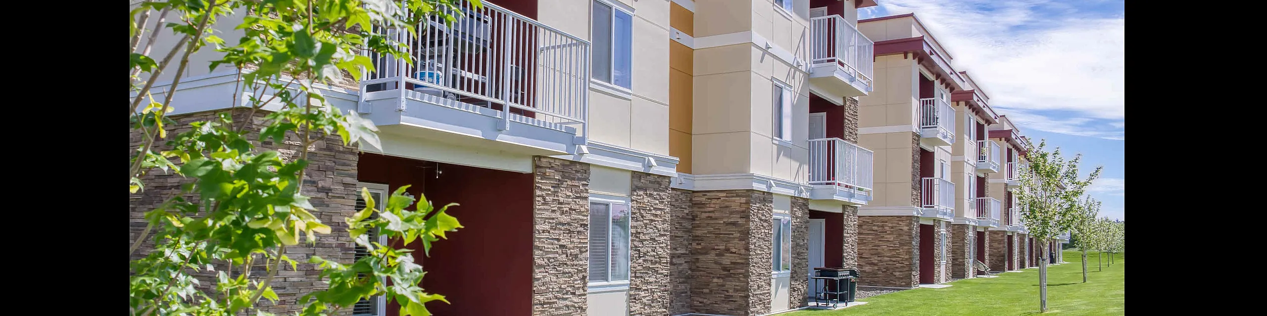 Modern apartment building with inviting balconies and lush green surroundings, perfect for relaxed living.