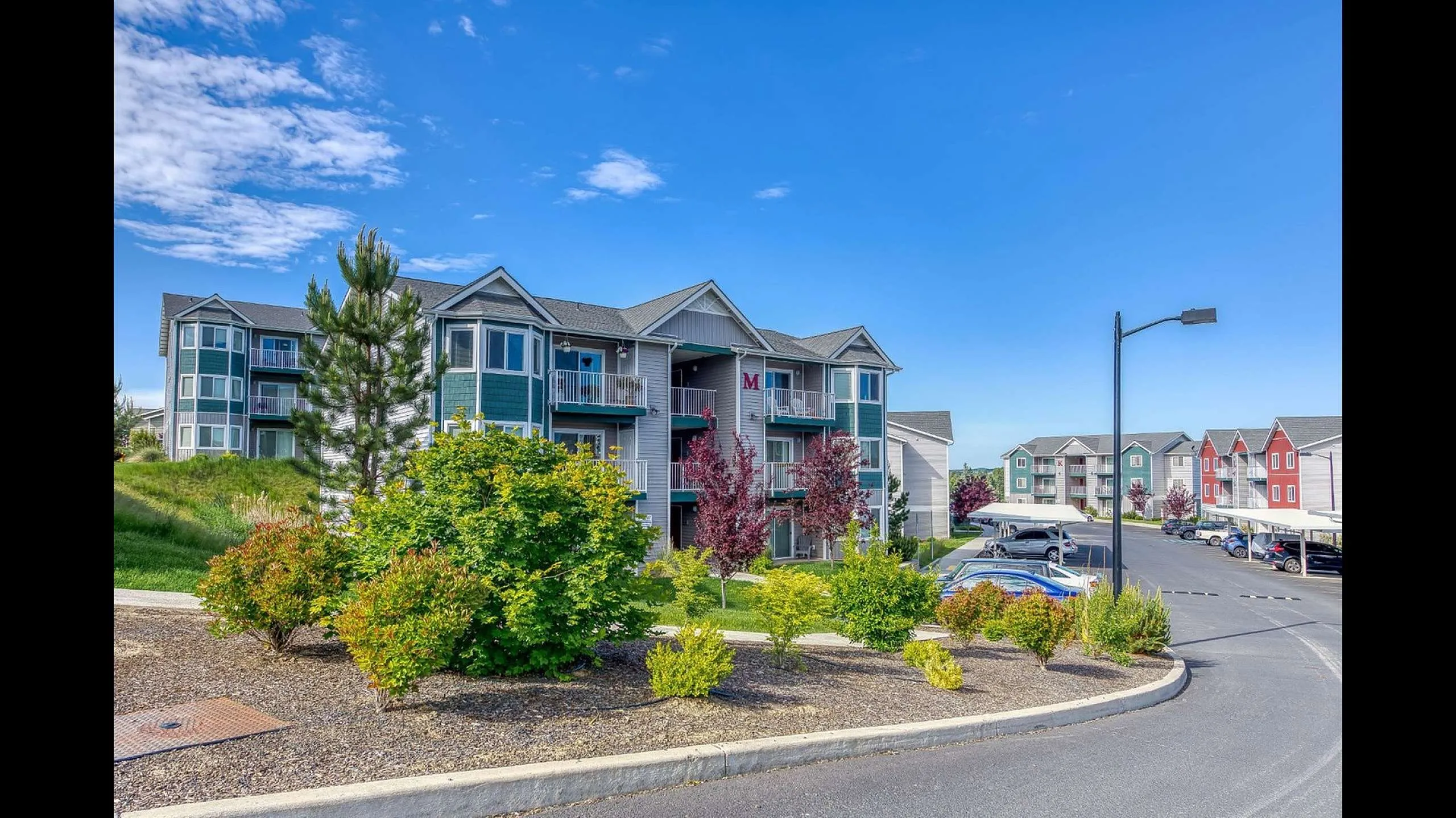 Charming apartment complex with vibrant landscaping and modern architecture, nestled in a serene neighborhood with ample parking and scenic views.