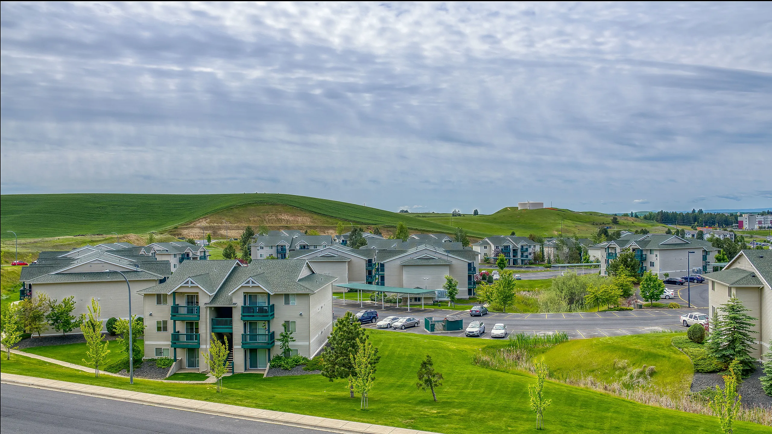 Charming apartment community nestled amidst lush green hills and expansive lawns, offering serene surroundings and modern living.