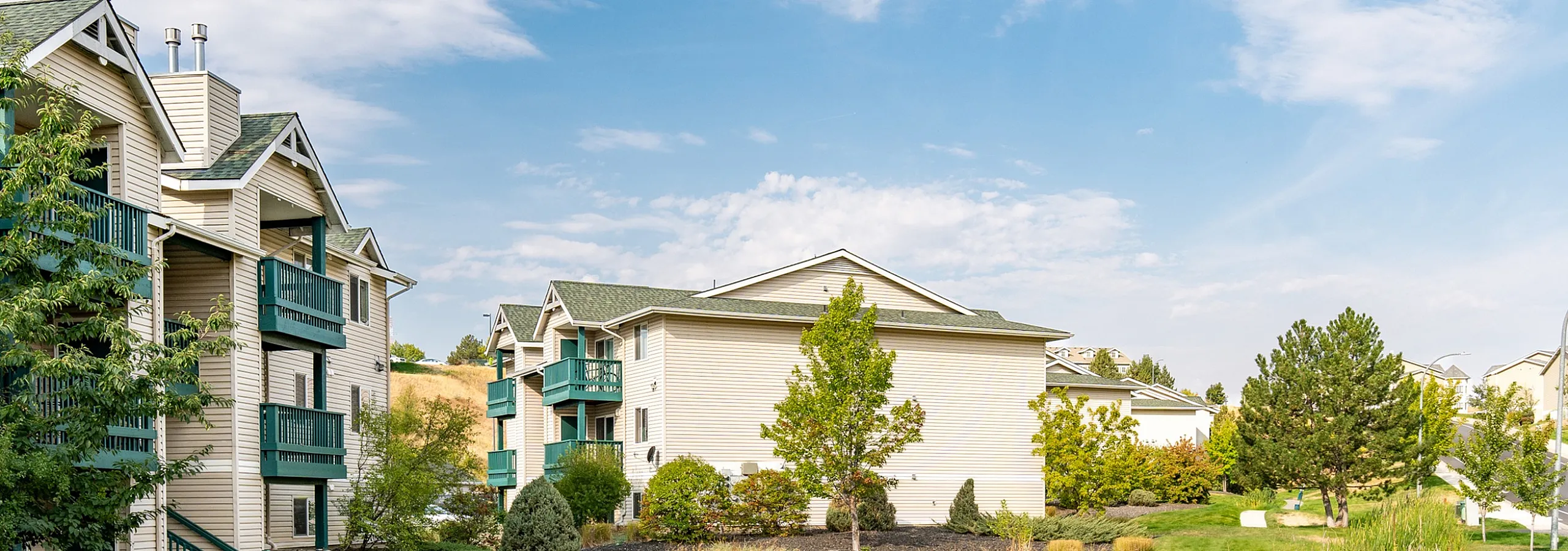 Charming apartment complex surrounded by lush greenery and serene landscaping, featuring cozy balconies and picturesque outdoor spaces.