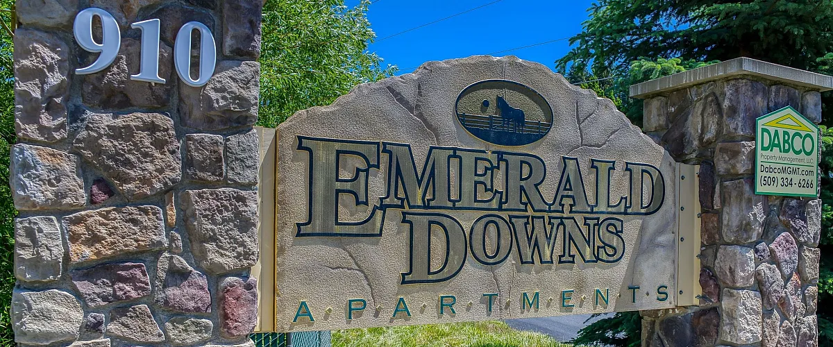 Charming stone entrance sign for Emerald Downs Apartments, exuding a welcoming and cozy vibe amidst lush greenery.