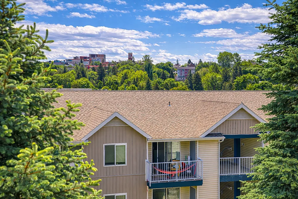 Charming apartment with a sunny balcony surrounded by lush greenery and vibrant urban skyline views.